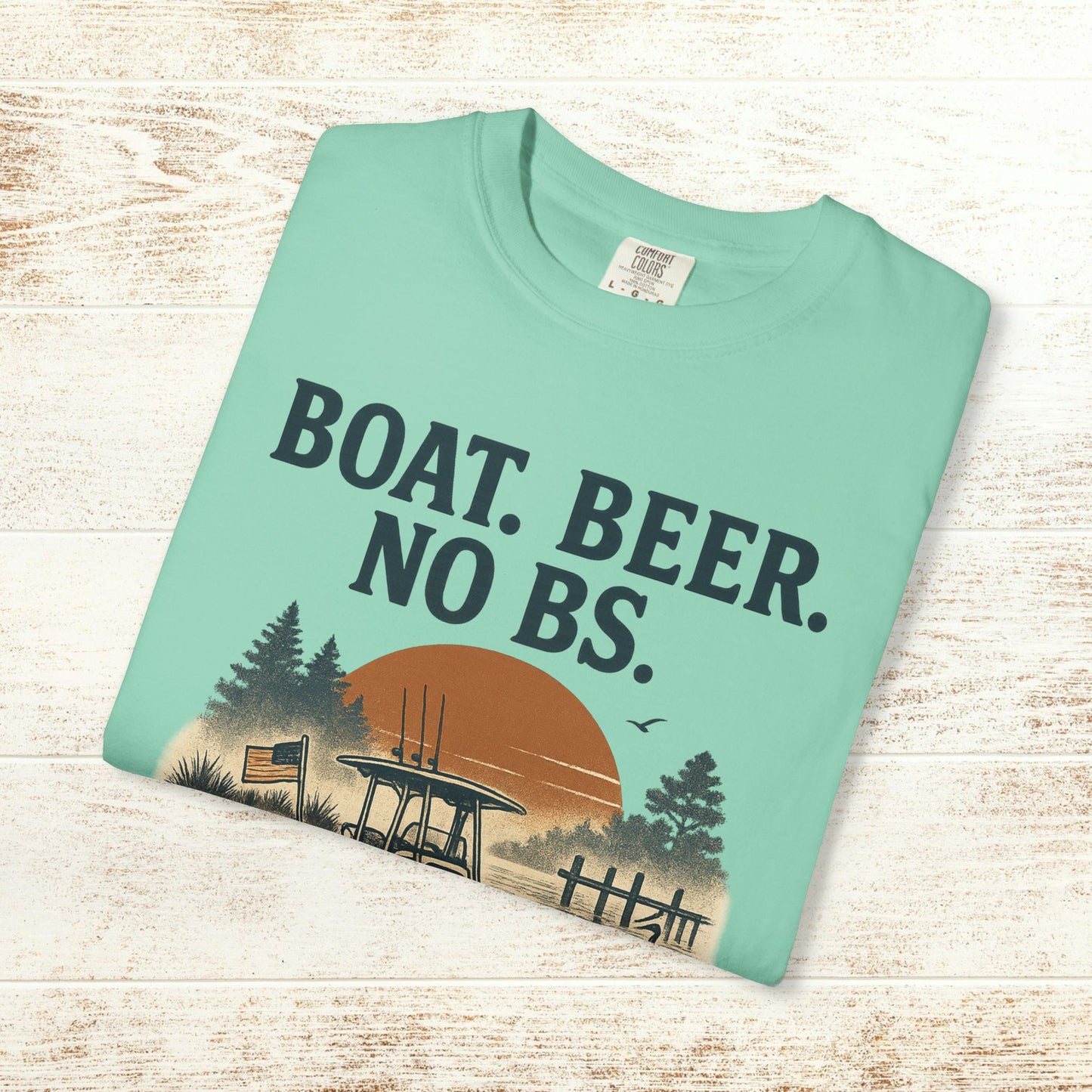 Boat Beer No BS Tee displayed on a wooden background, featuring a vibrant design with a sunset and natural elements.