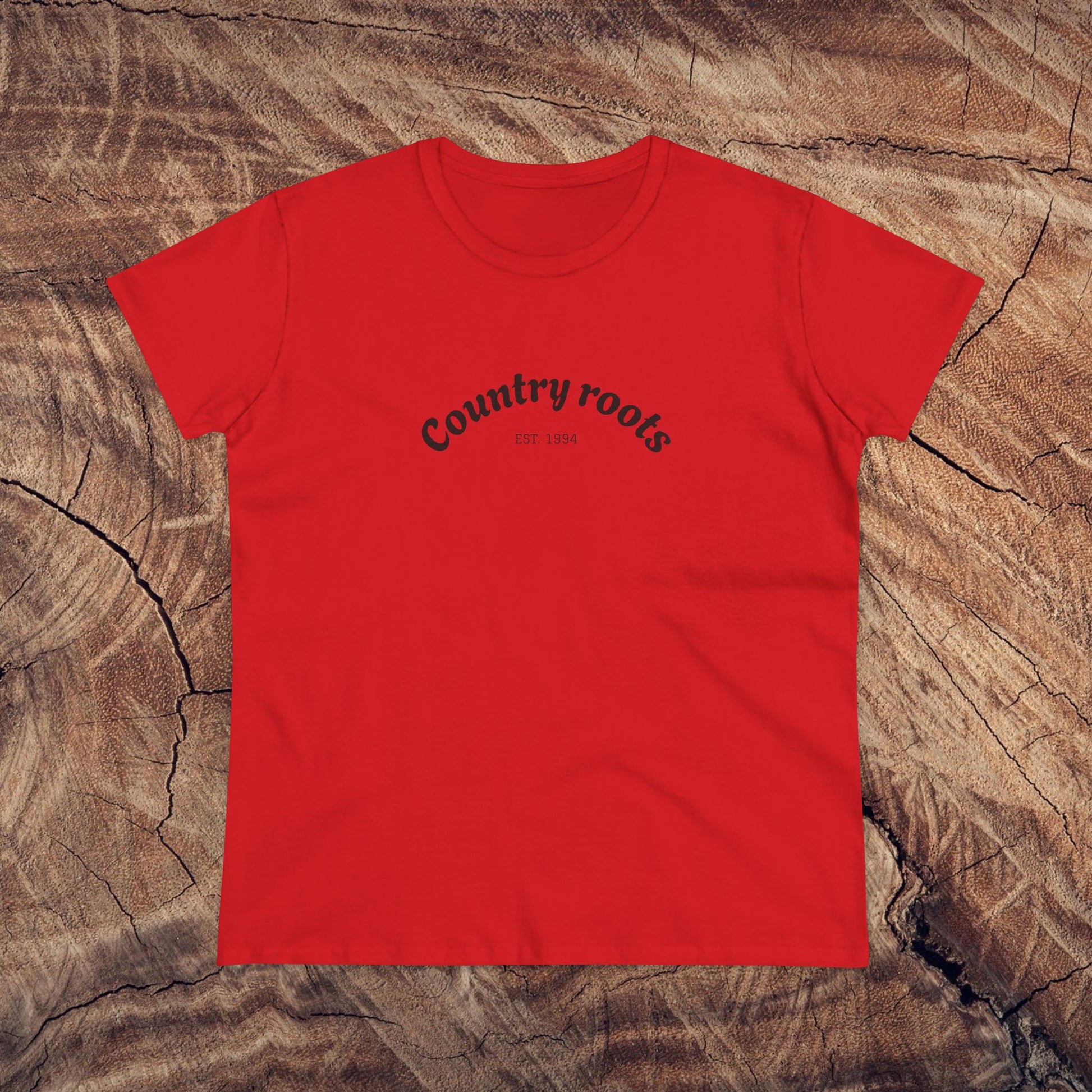Bold red Country Roots Cowgirl Tee displayed against a textured wooden backdrop, highlighting the 'Country roots EST 1984' design. A fantastic addition to any casual wardrobe.