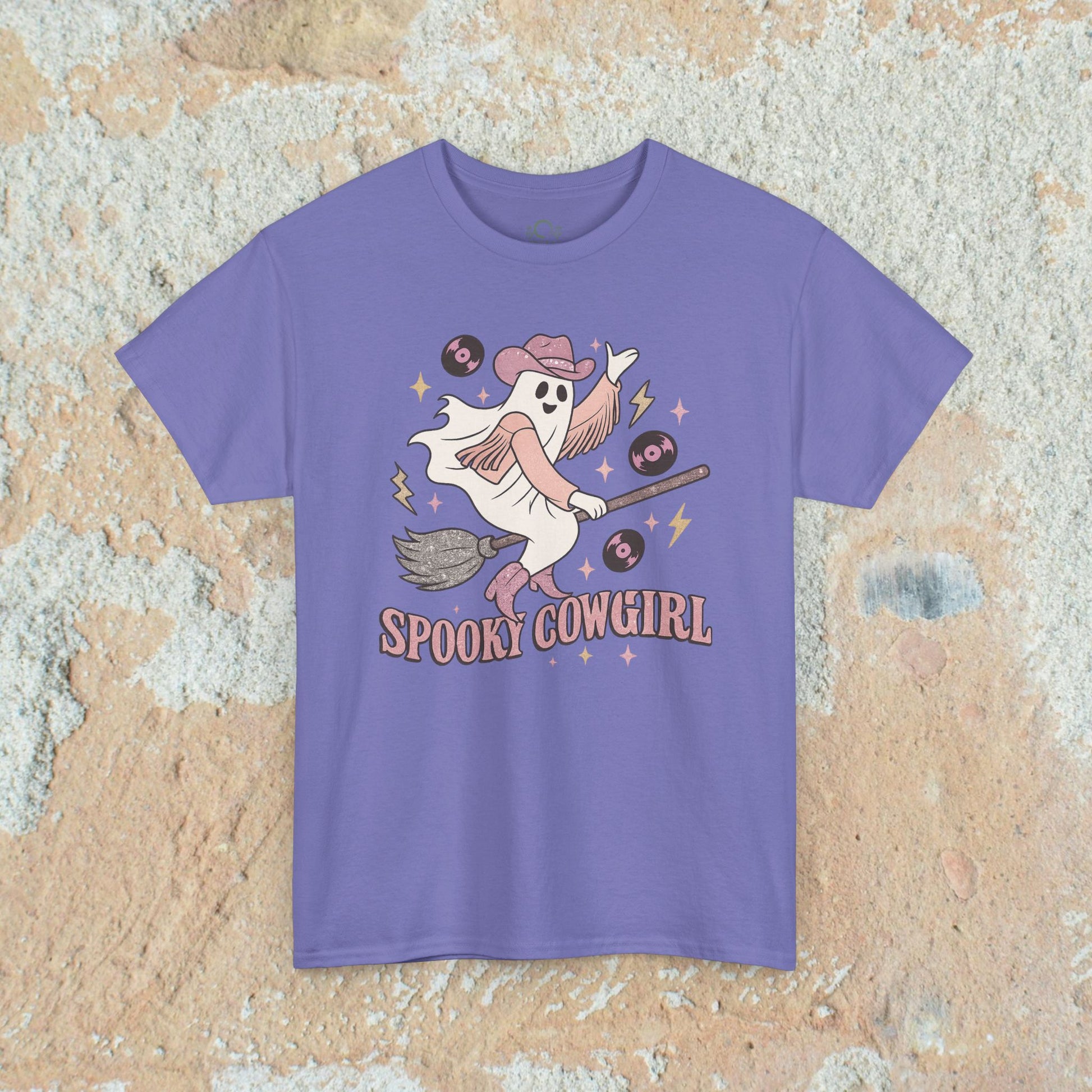 Spooky Cowgirl Graphic Tee in purple, featuring a whimsical ghost wearing a cowboy hat, riding a broomstick surrounded by vinyl records. Soft and eco-friendly fabric, available in sizes S-5XL.