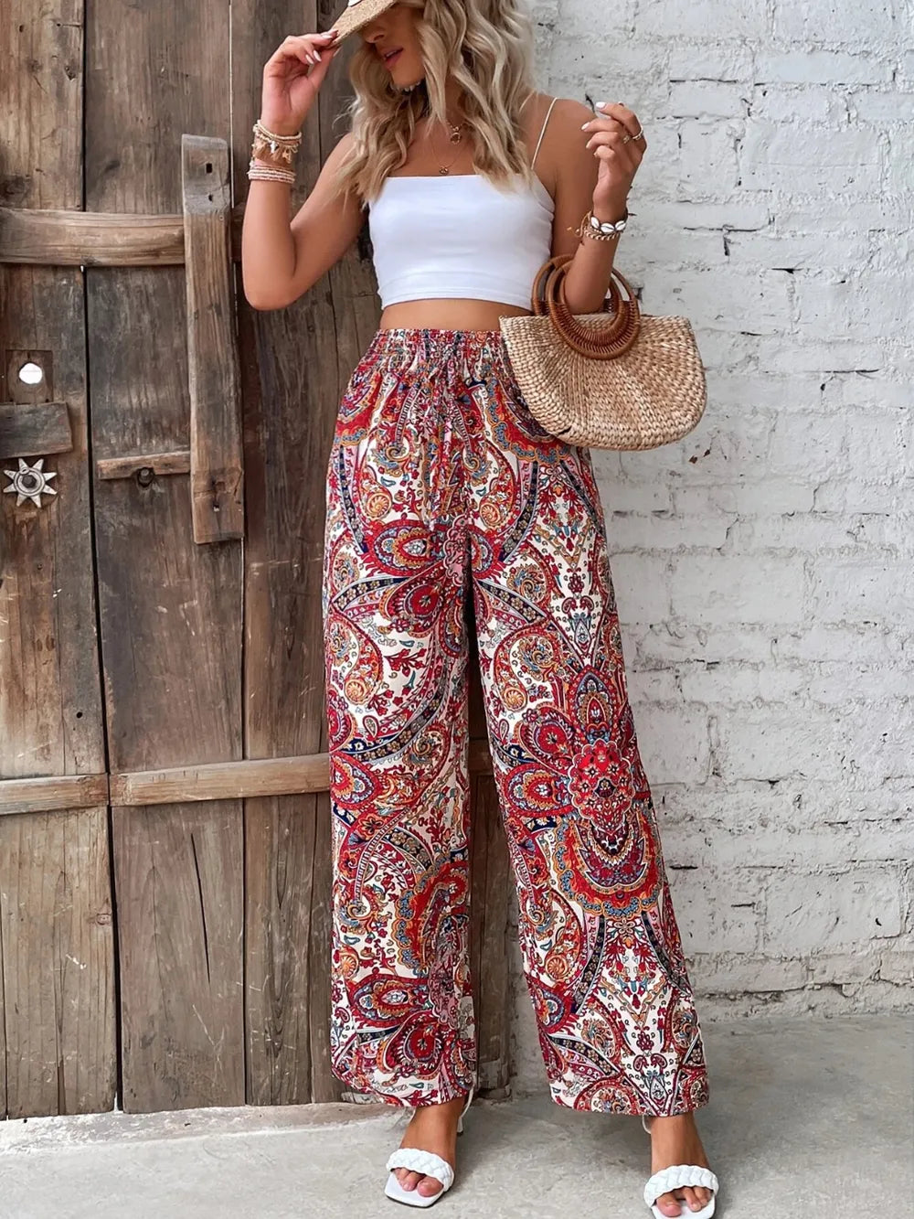 Trendy Printed Wide Leg Pants with Tied Detail, featuring vibrant paisley patterns, paired with a white crop top and a stylish straw handbag for a perfect summer look.