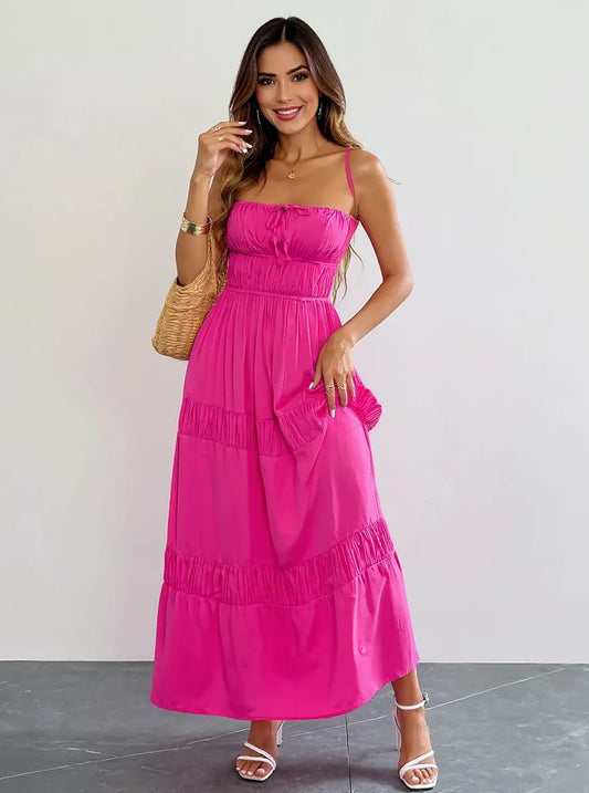 Tied Back Tiered Maxi Cami Dress in vibrant pink, featuring a ruched bodice and adjustable straps, styled with a fashionable woven bag and strappy heels.