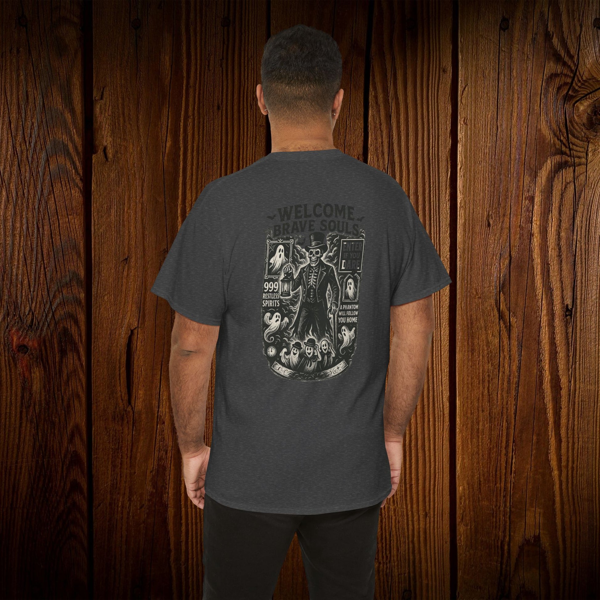 Back view of a Spooky Halloween Graphic Tee displaying a welcome design, modeled by a man, perfect casual wear for Halloween, shown against a wooden backdrop.