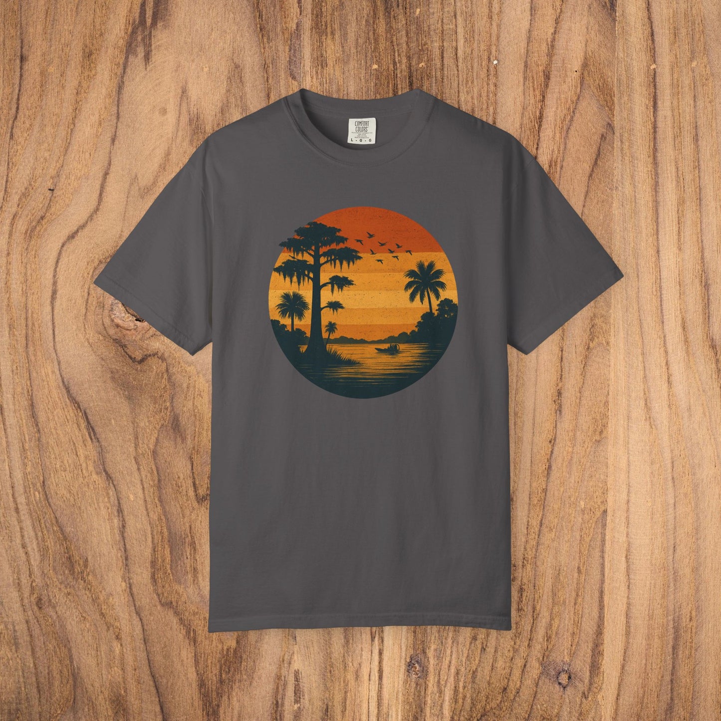 Unisex Garment-Dyed Sunset Tee in dark gray featuring a vibrant sunset graphic with palm trees, ideal for casual wear.