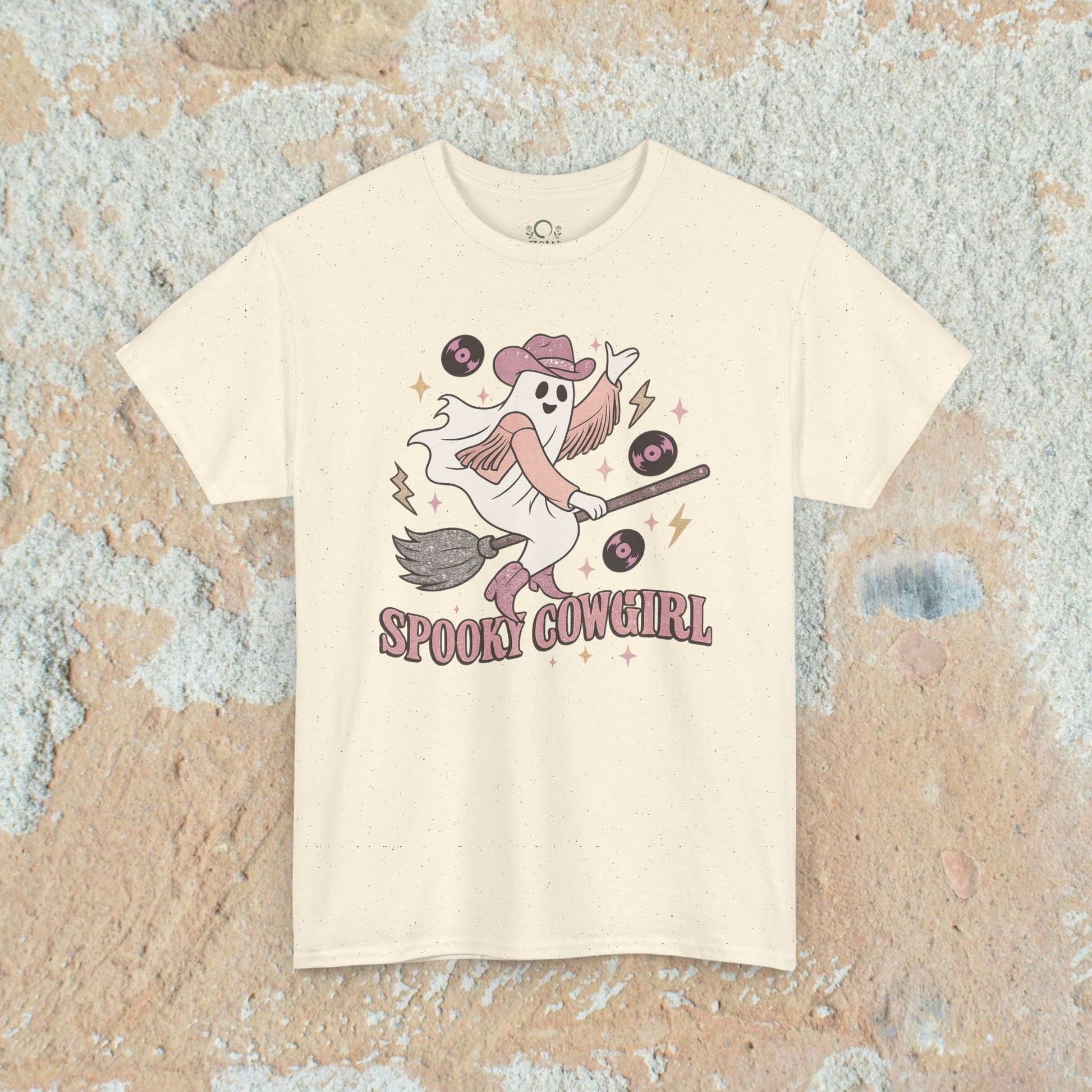 Spooky Cowgirl Graphic Tee - Soft Fabric, Eco-Friendly, Sizes S-5XL, featuring a charming ghost cowgirl with a broom on a cream speckled background.
