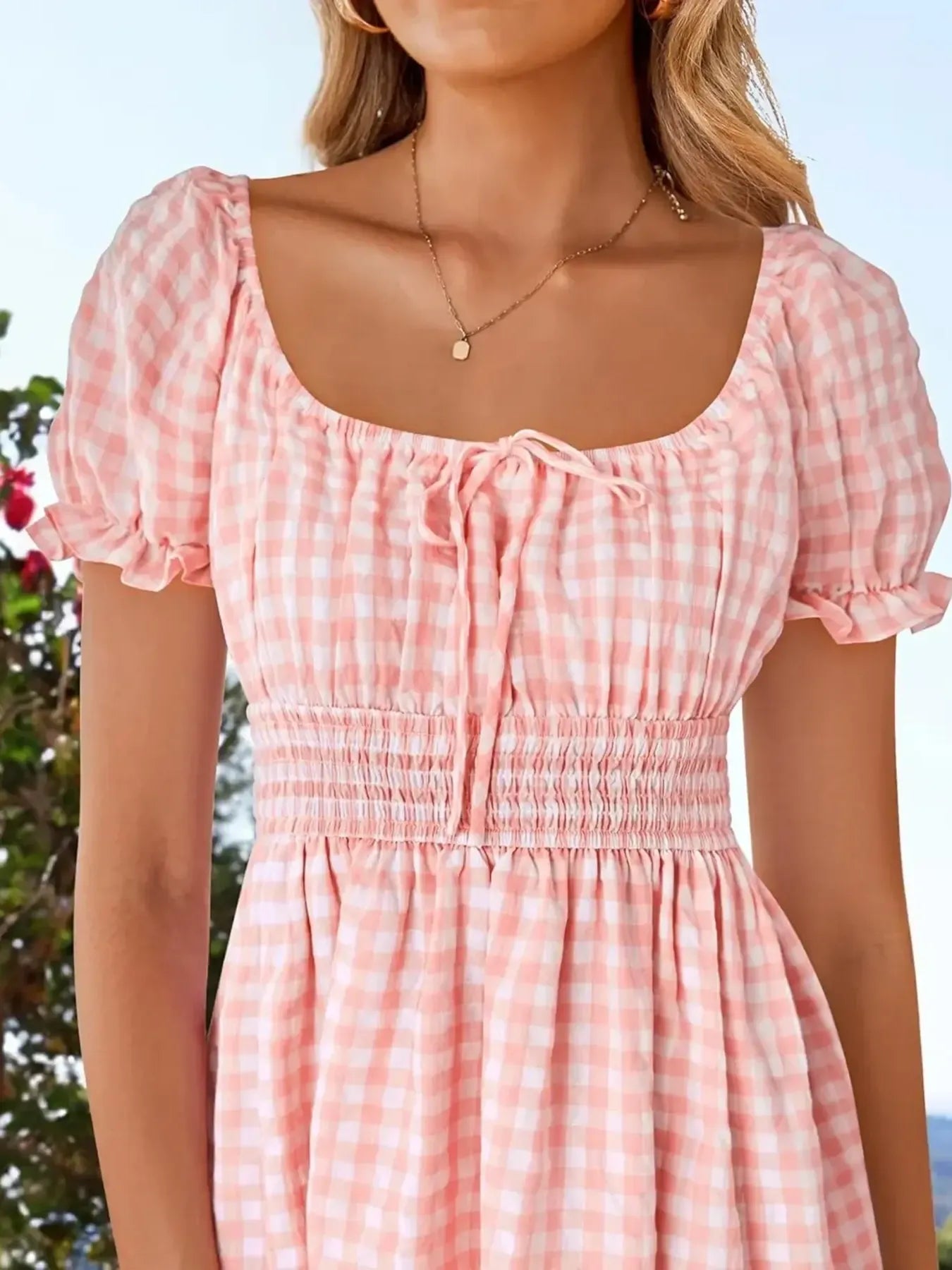 Close-up of Women's Gingham Puff Sleeve Smocked Dress in pink, highlighting the smocked bodice and tie details for a feminine summer look.