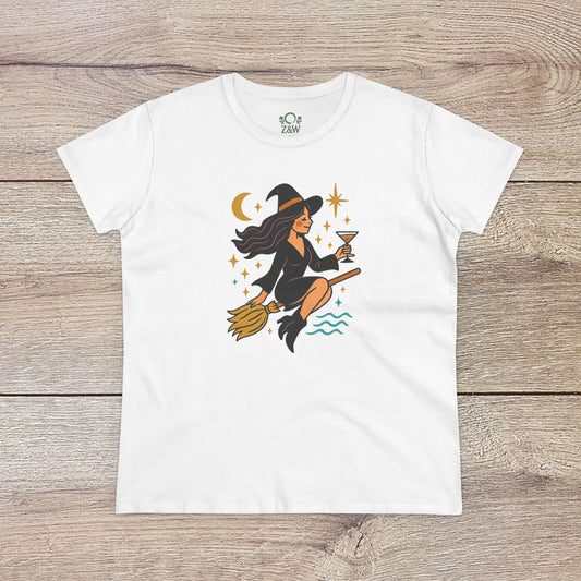 Witchy Night Out Tee featuring a stylish illustration of a witch flying on a broomstick with an hourglass, set against a cosmic backdrop, made from 100% cotton and ethically produced.