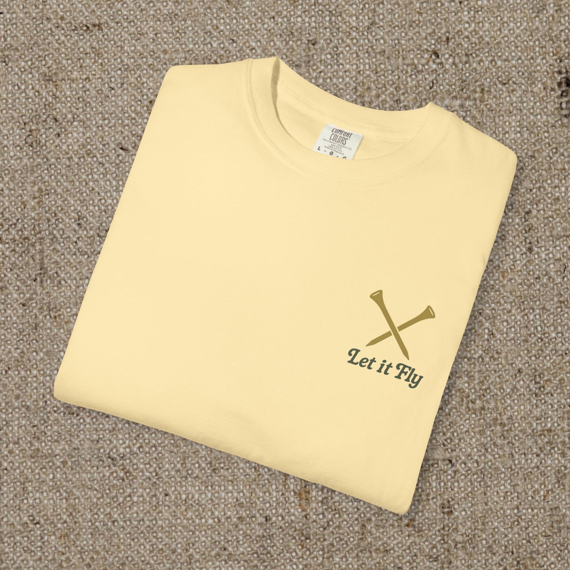 Flat lay of the yellow Tee It High Let It Fly Graphic Tee, emphasizing the minimalist graphic of crossed golf tees and the slogan.