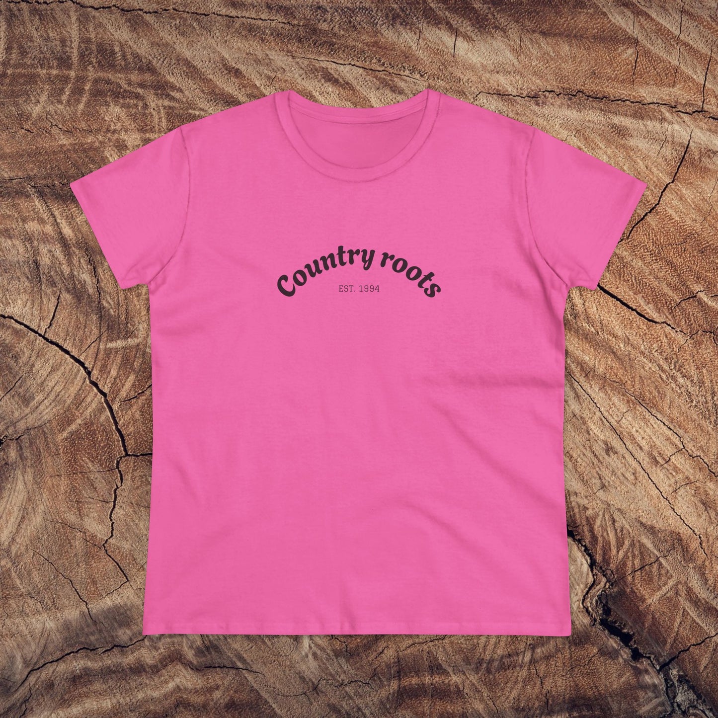 Stylish pink Country Roots Cowgirl Tee on a wooden background, featuring the slogan 'Country roots EST 1984'. Perfect for casual everyday wear.