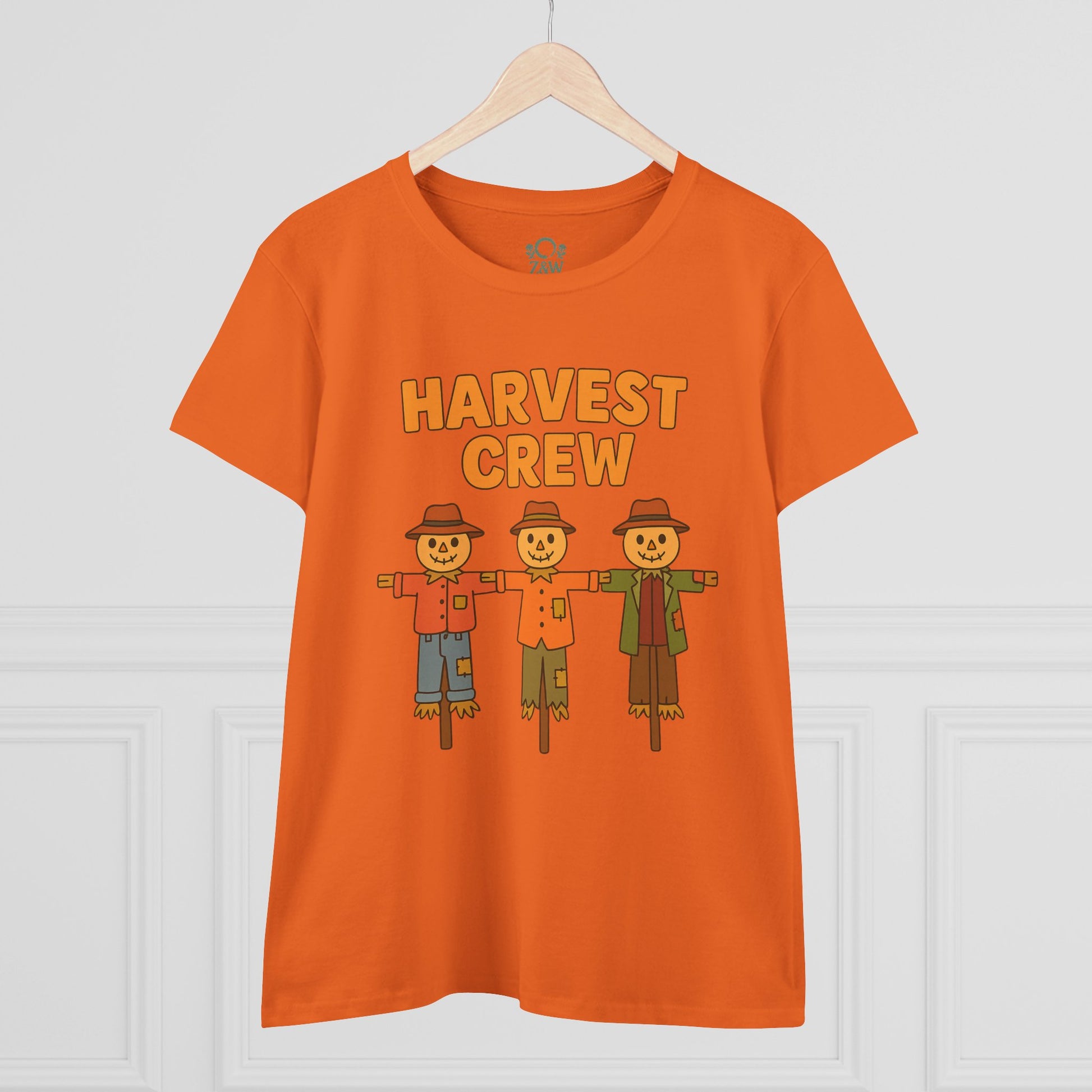 Harvest Crew Halloween T-Shirt displayed on a hanger in bright orange, featuring three playful scarecrows, emphasizing its comfortable fit and fabric.