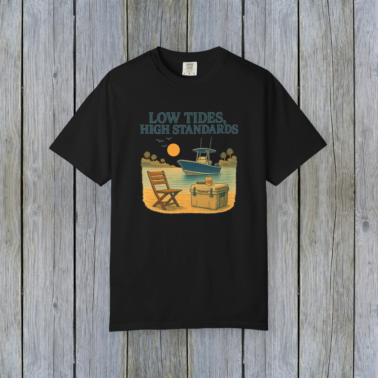 Garment-Dyed Low Tides High Standards T-Shirt in black, featuring a relaxing beach scene with a chair and boat. Made from soft 100% US cotton, available in sizes S-4XL.