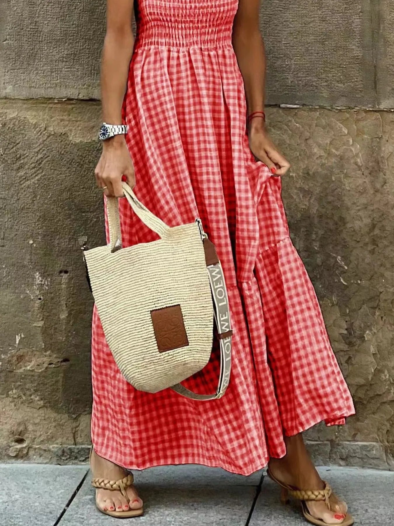 Stylish close-up of a woman wearing a Gingham Maxi Dress with Ruffle Straps, Smocked Bodice & Tiered Design in red, highlighting the flow of the dress with a straw bag.