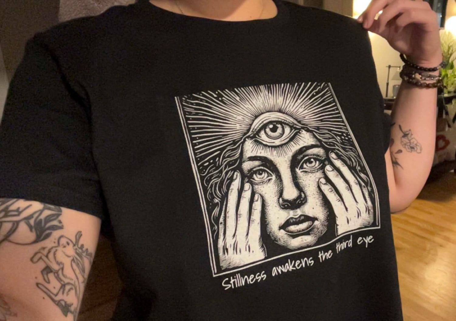 Stylish Third Eye Graphic Tee featuring a unique design with a woman holding her face, emphasizing the phrase 'Stillness awakens the third eye', made from 100% cotton, showcasing a cropped fit and durable comfort.