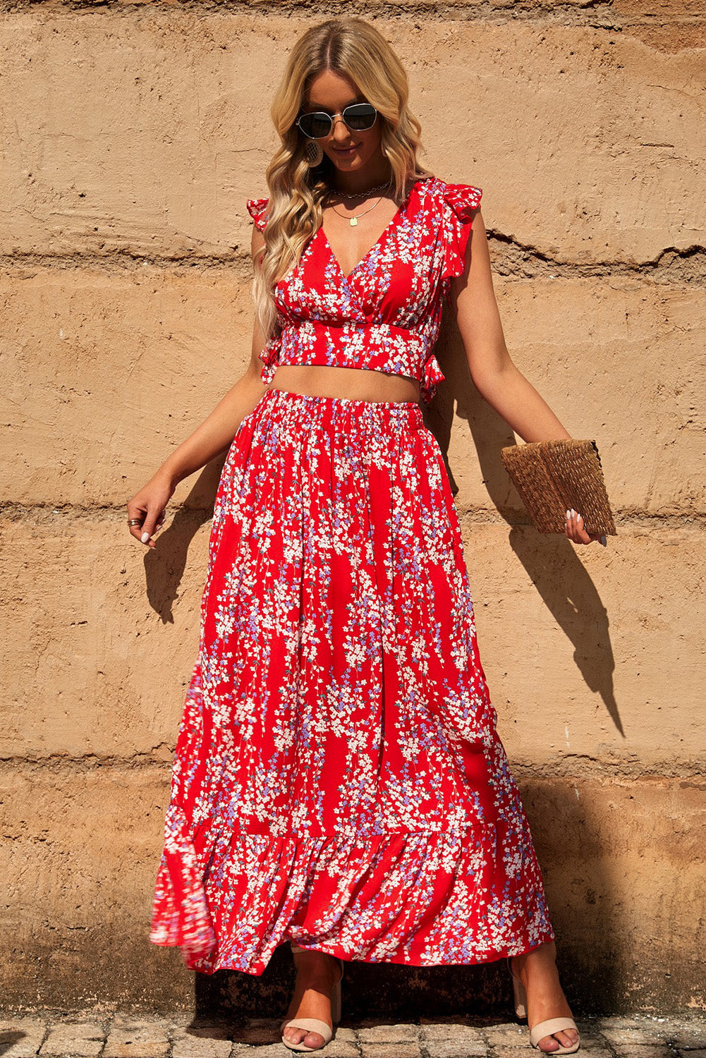 Close-up of a model in a Floral Print Tie-Back Cropped Top & Maxi Skirt Set against a rustic wall, emphasizing the stylish summer ensemble's vibrant colors and patterns.
