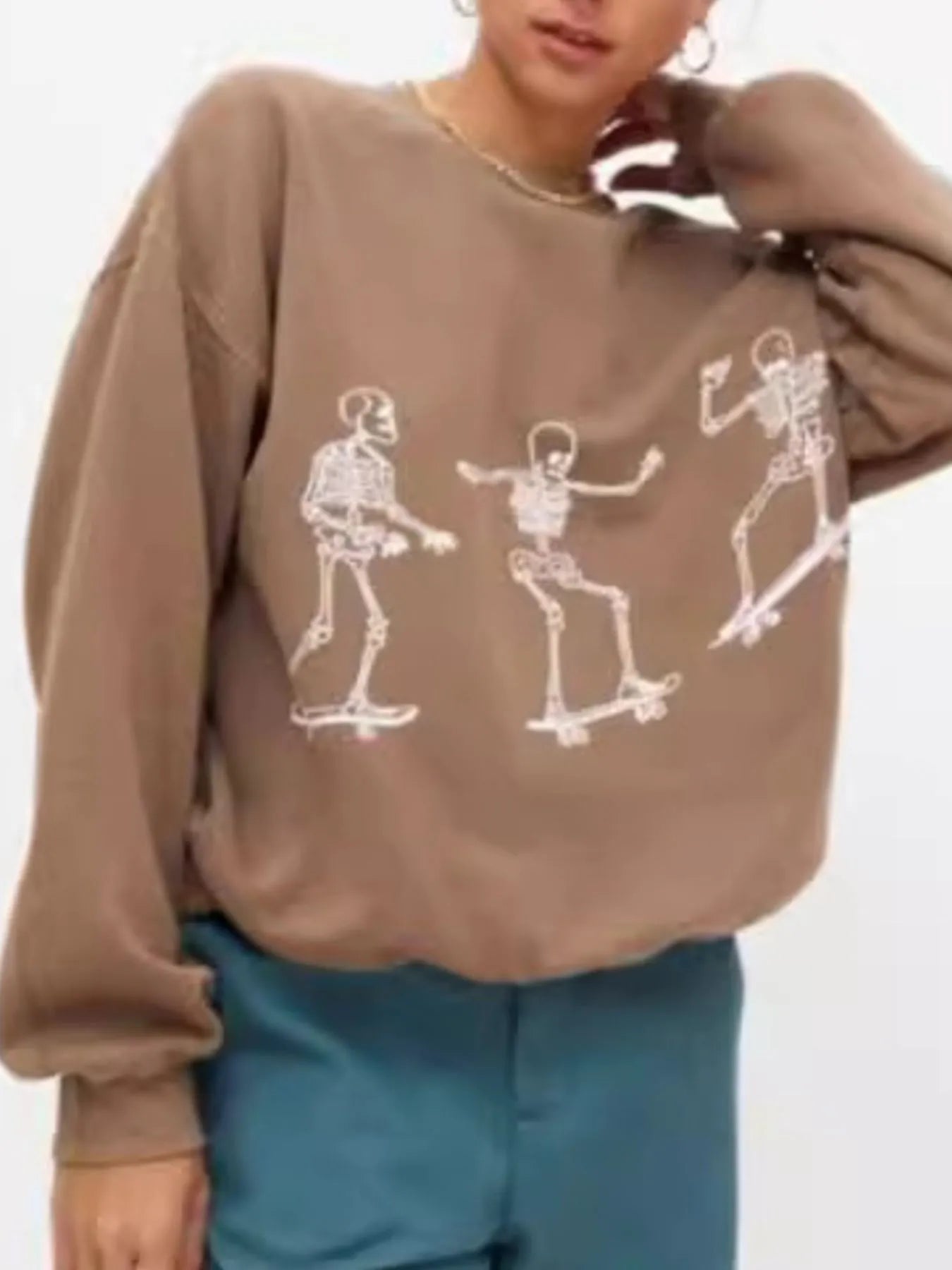 Front view of the Oversized Skeleton Graphic Sweatshirt for Women showcasing a stylish oversized fit and multiple skeleton illustrations on a brown background.