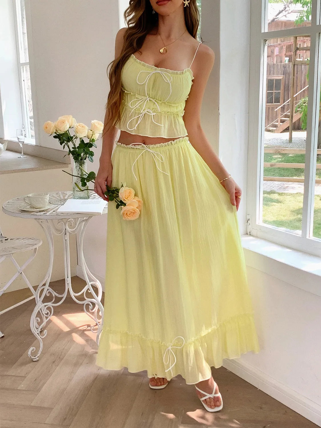 Model posing in a Two-Piece Frill Square Neck Cami and Ruched Skirt Set in Stretchy Lyocell Blend, with a vibrant yellow color, holding roses.