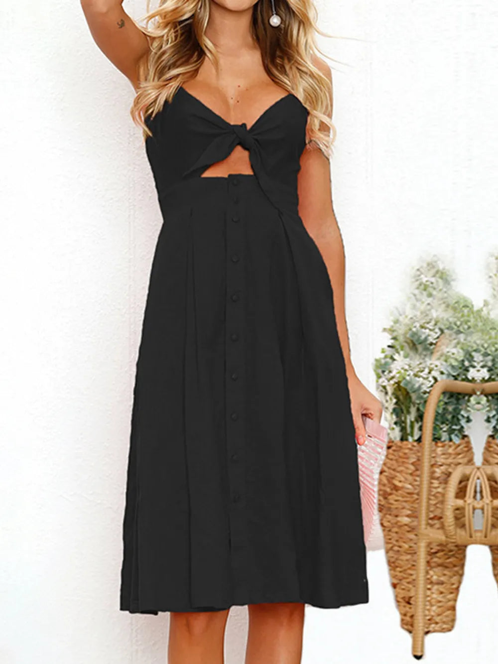 Front view of the Cutout Smocked Sweetheart Neck Cami Dress with Decorative Button and Opaque Design in black color, featuring a stylish tied top.