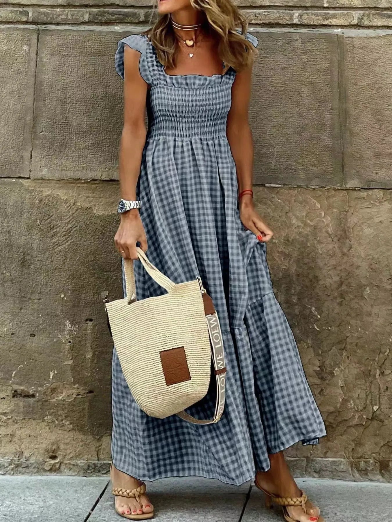 Stylish woman wearing a Gingham Maxi Dress with Ruffle Straps, Smocked Bodice & Tiered Design by Trendsi, holding a straw bag, perfect for summer outings.