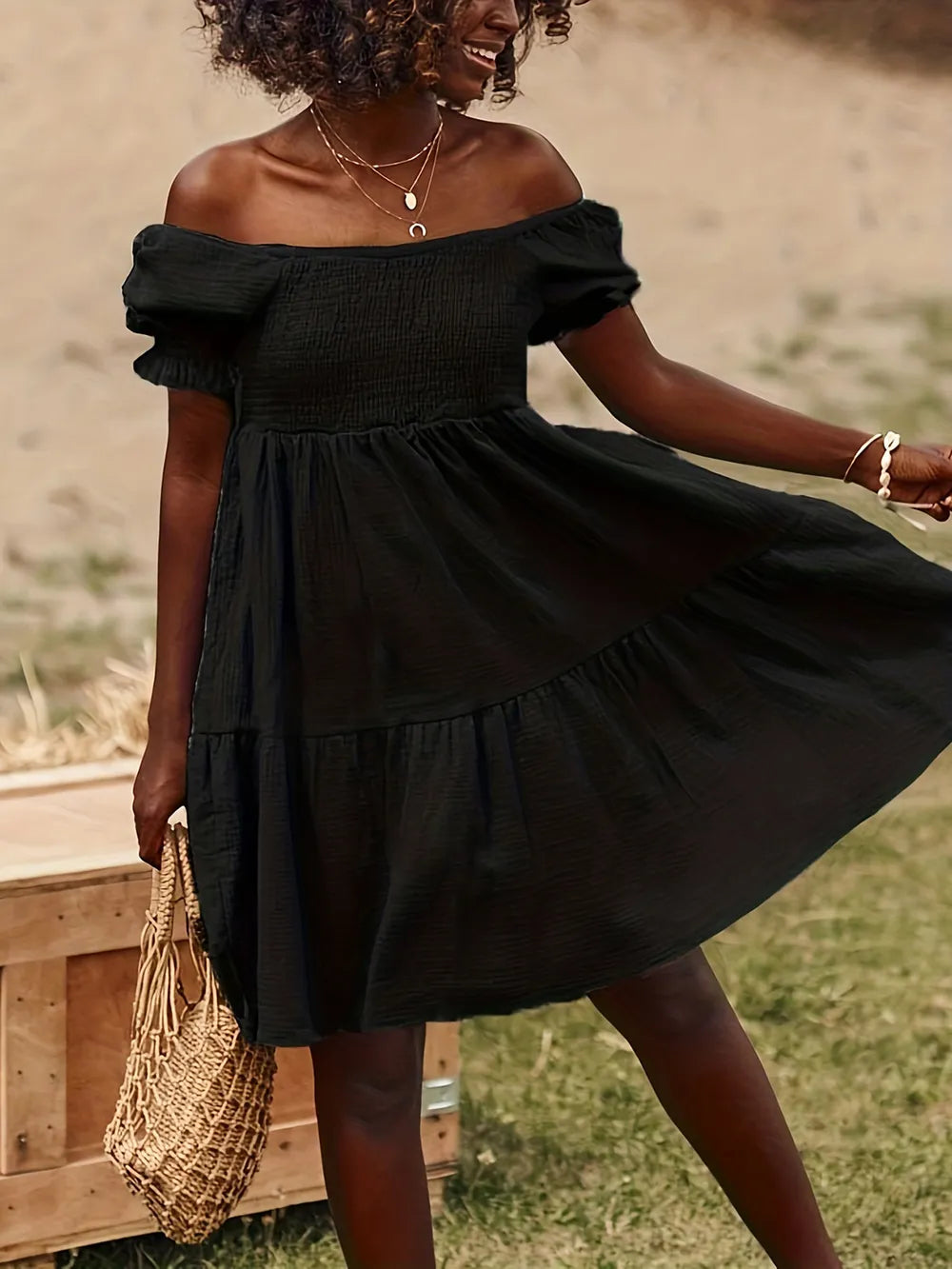 Full Size Ruffled Off-Shoulder Dress with Short Sleeves in an outdoor setting, showcasing a bohemian vibe with a flowing black design.
