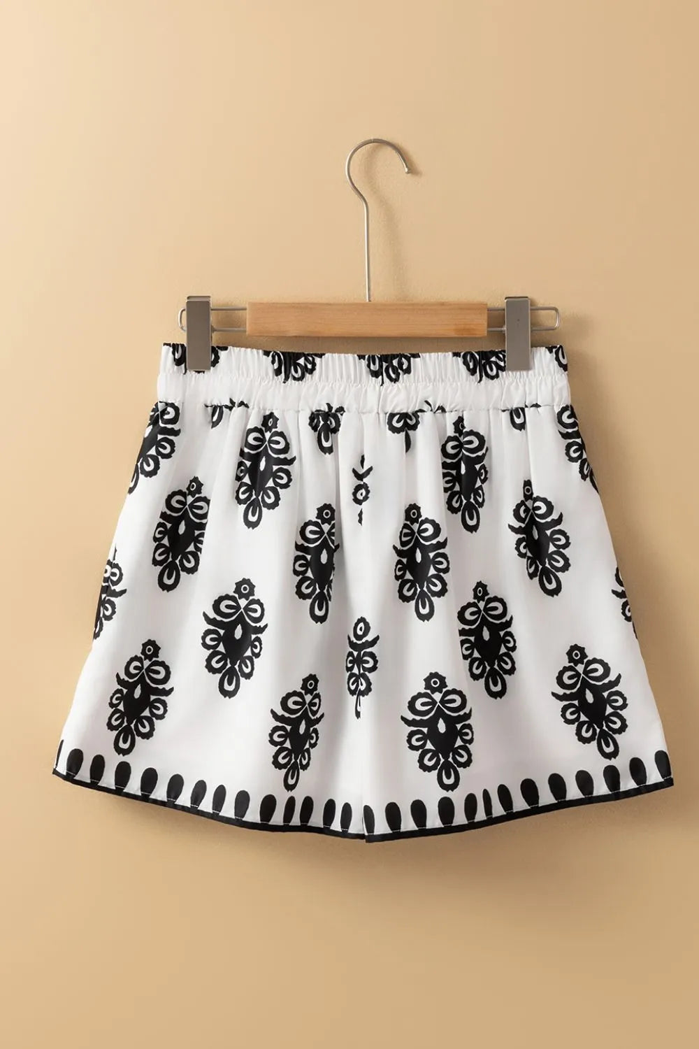 Tied Printed Shorts hanging on a wooden hanger, highlighting their trendy black and white design, a must-have addition to your summer wardrobe.
