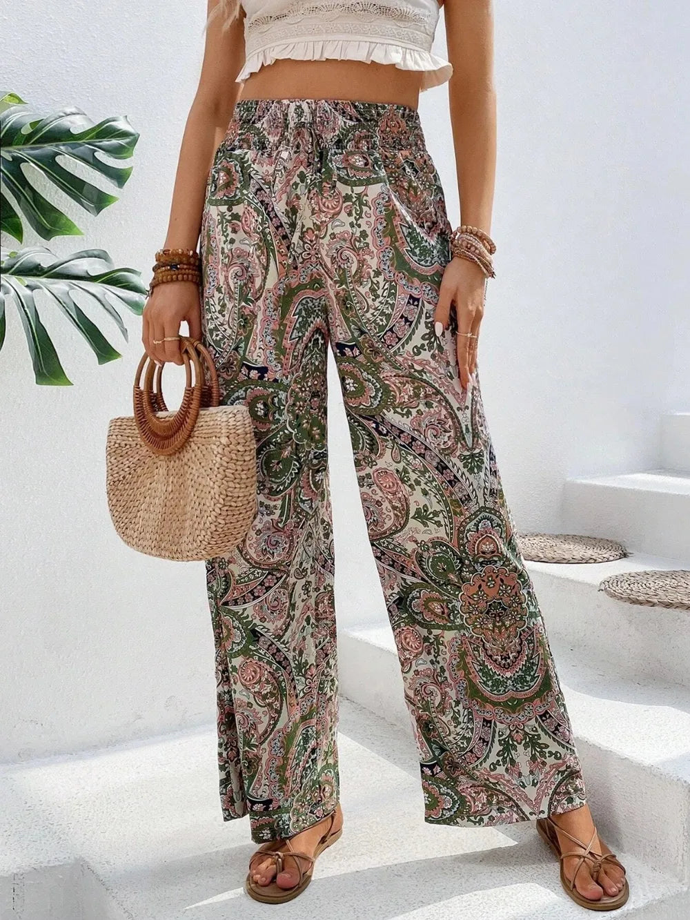 Trendy Printed Wide Leg Pants with Tied Detail, flaunting an eye-catching paisley pattern and paired with a light crop top and a fashionable straw bag, suitable for any occasion.