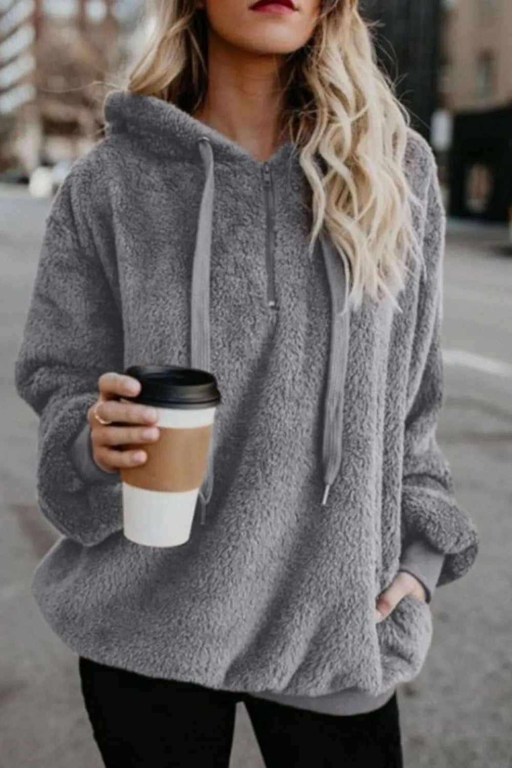 Cozy Full Size Teddy Hoodie with Quarter-Zip and Drawstring, Opaque & Slightly Stretchy, 100% Polyester, modeled by a woman in the city, holding a coffee cup.