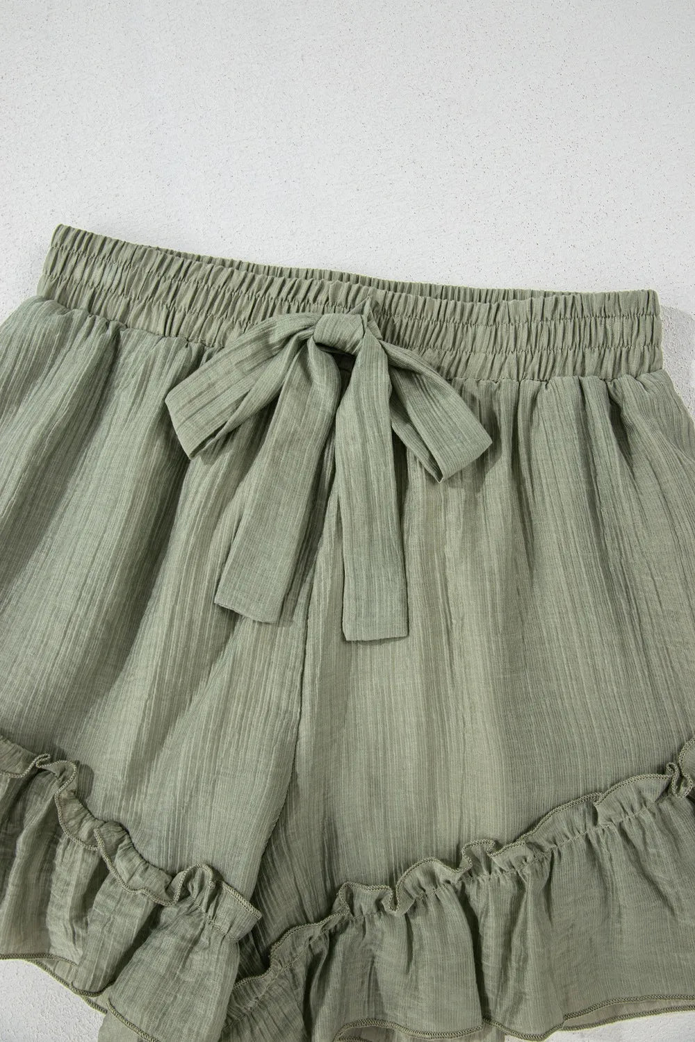 Close-up of the tie detail on the Textured Tie Waist Ruffle Hem Shorts, highlighting the unique textured fabric and stylish design.