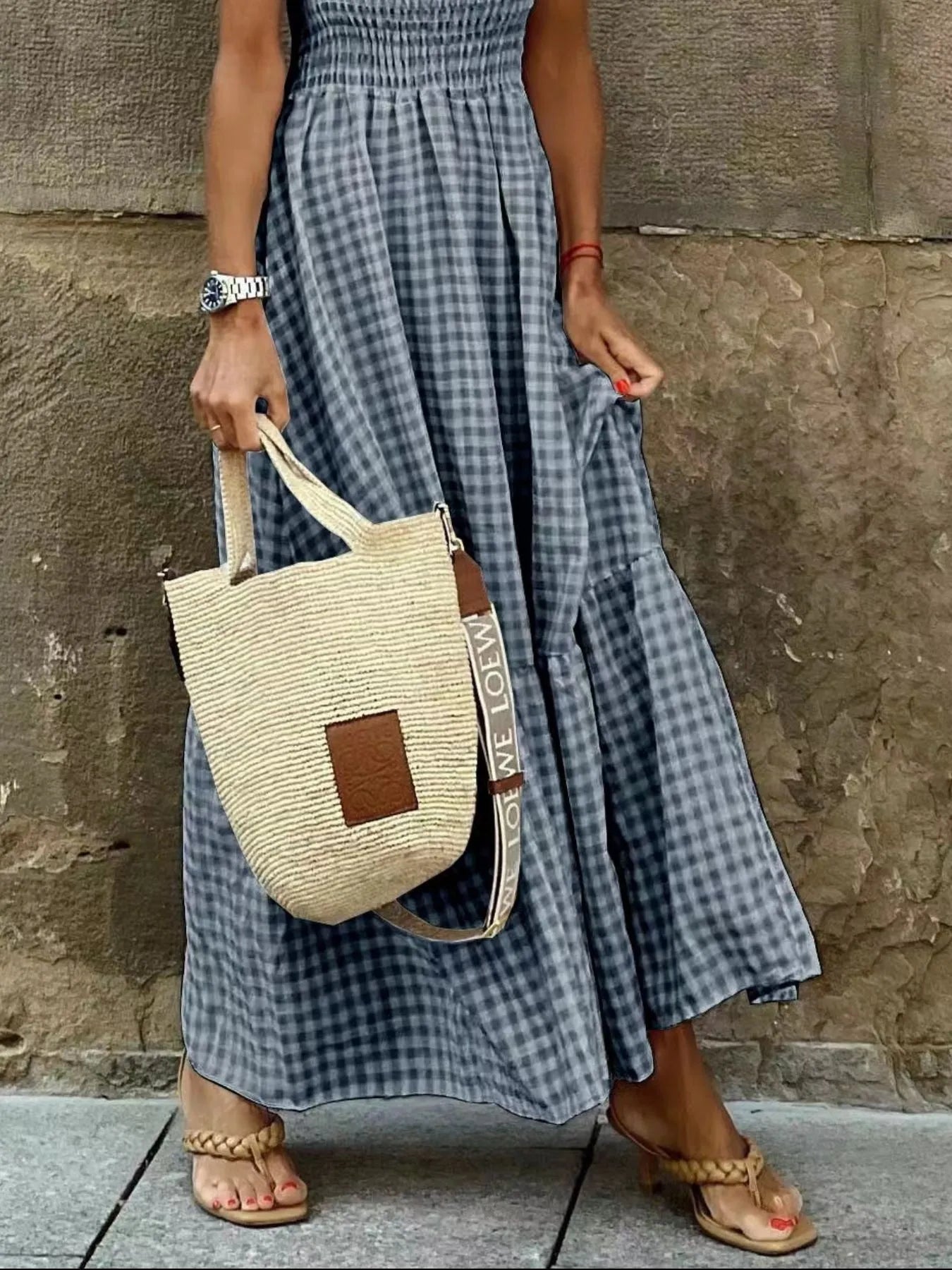 Detail shot of a Gingham Maxi Dress with Ruffle Straps, Smocked Bodice & Tiered Design by Trendsi, highlighting the flowy skirt and stylish straw bag.