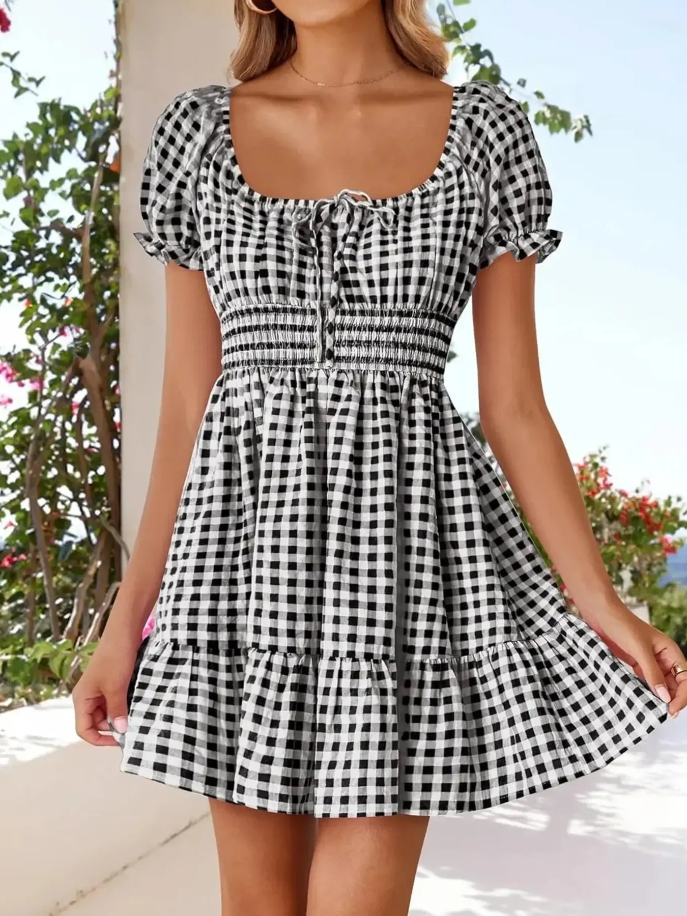 Women’s Gingham Puff Sleeve Smocked Dress featuring a lightweight design and stretchy fabric, showcased outdoors with a scenic background.