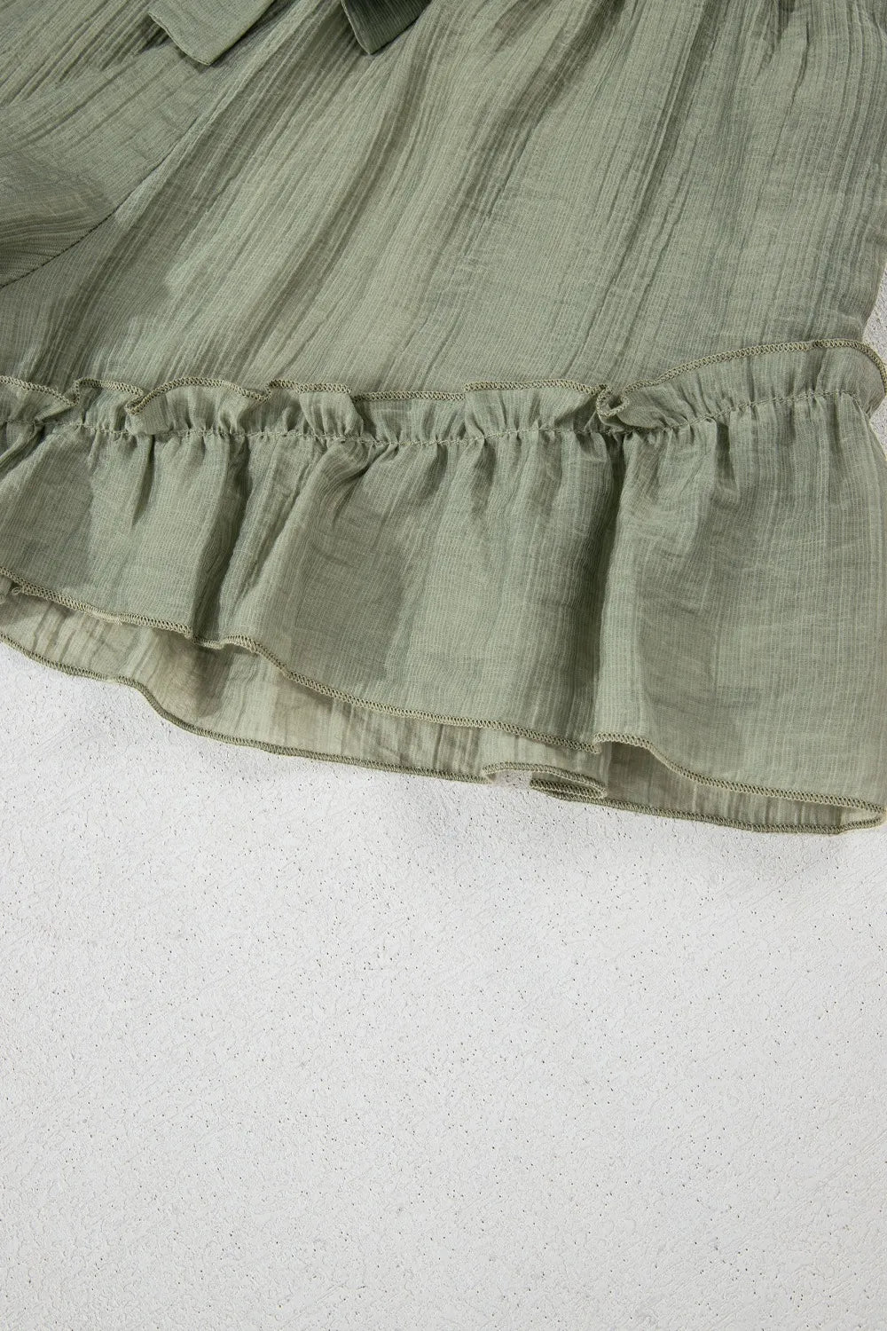 Close-up shot of the ruffle hem of the Textured Tie Waist Ruffle Hem Shorts, showcasing the soft fabric and feminine design.