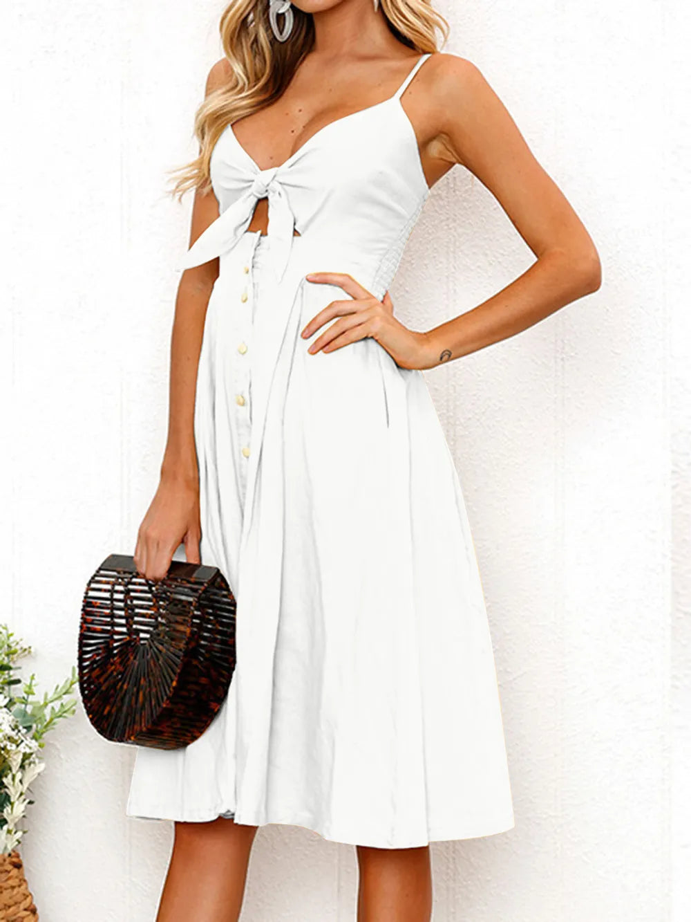 Side view of the Cutout Smocked Sweetheart Neck Cami Dress with Decorative Button and Opaque Design in white, featuring a charming tie detail at the front.