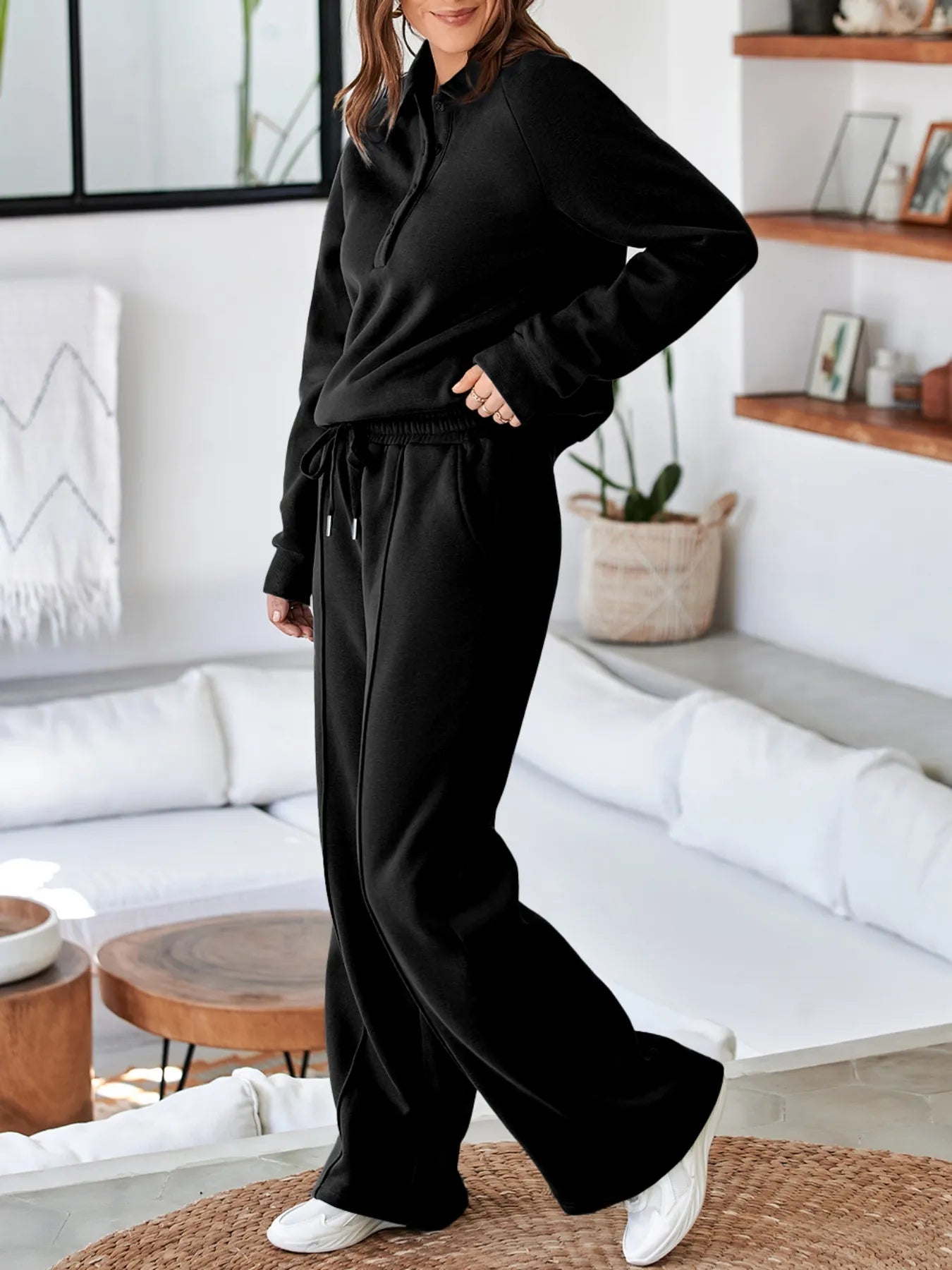 Woman wearing Trendsi Collared Sweatshirt & High Waist Pants Two-Piece Active Set in black, showcasing comfort and style in a modern living space.