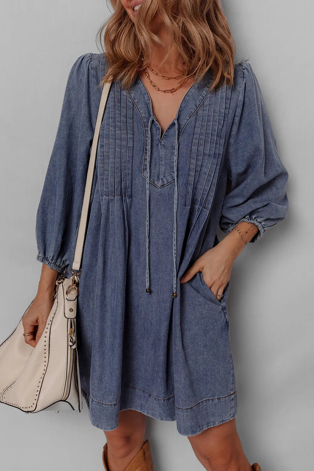 Close-up of a Tie Neck Long Sleeve Mini Denim Dress showcasing detailed pleating and pockets, ideal for trendy casual wear.
