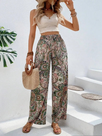 Trendy Printed Wide Leg Pants with Tied Detail in a colorful paisley pattern, elegantly styled with a crop top and accessories. 100% opaque polyester for comfort and style.