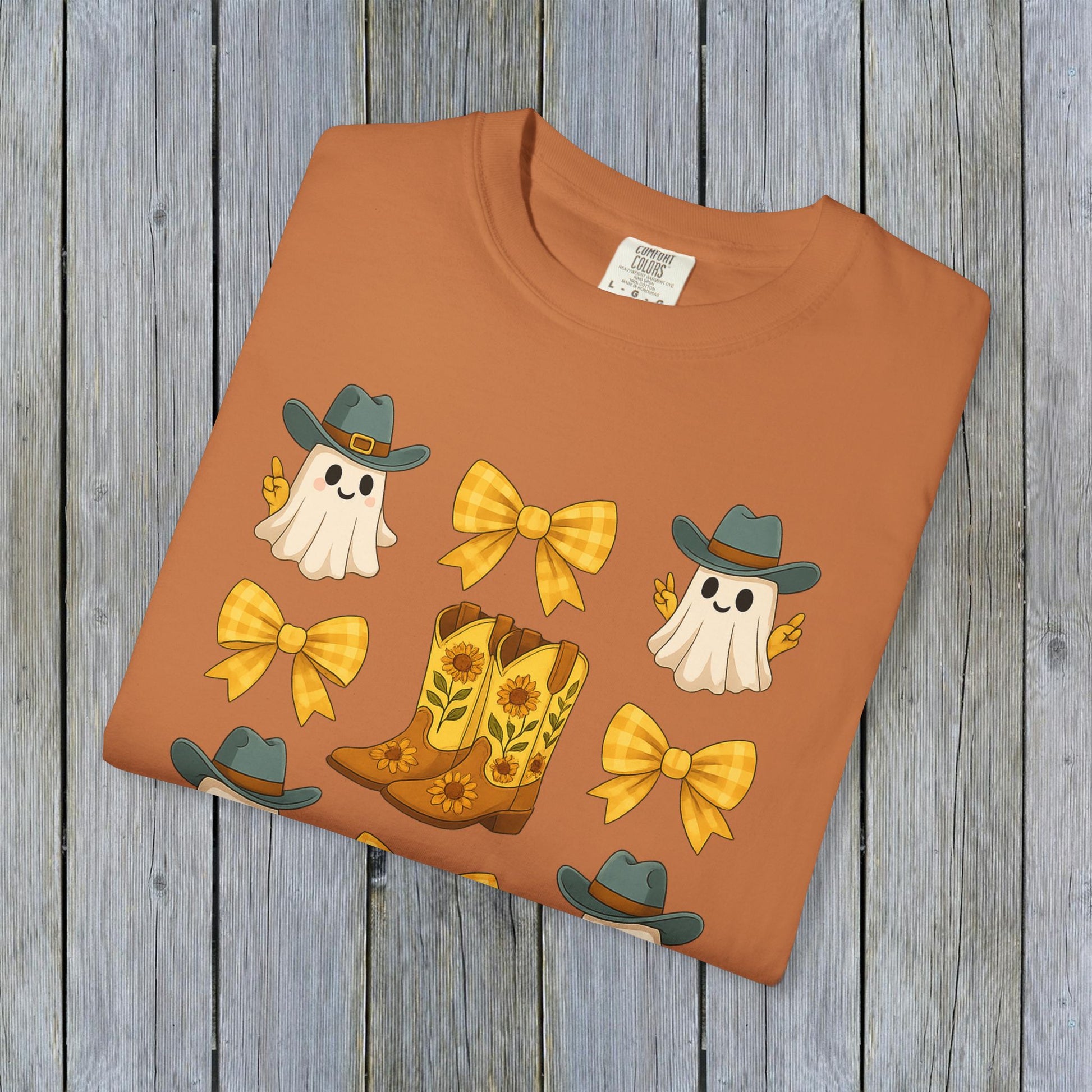Cute Halloween T-Shirt in warm orange color, adorned with cheerful ghosts and cowboy boots, made from sustainable materials for autumn styling.