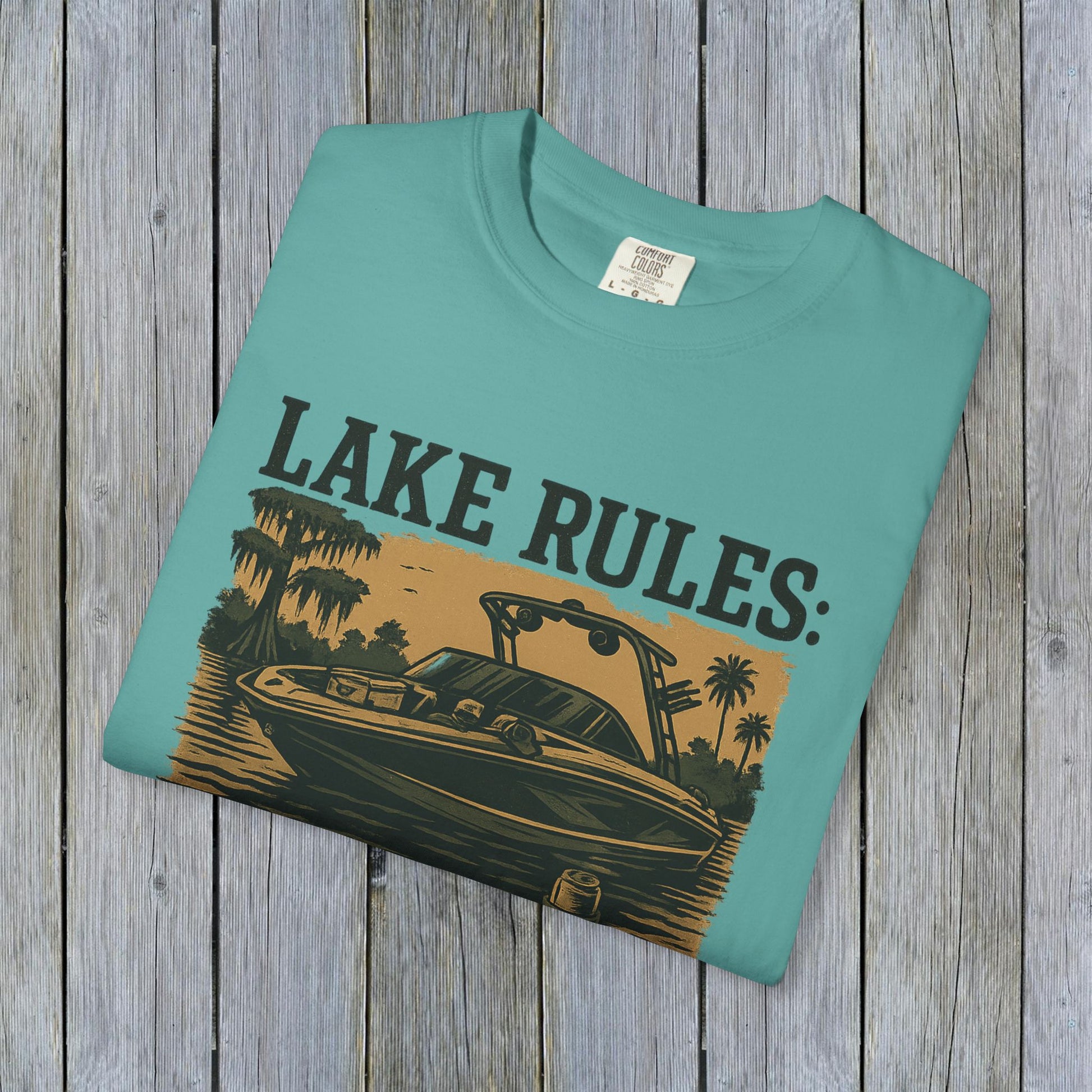 Front view of the Unisex Garment-Dyed Lake Rules Tee in teal, featuring a boat graphic with the text 'Lake Rules:', perfect for lake enthusiasts.