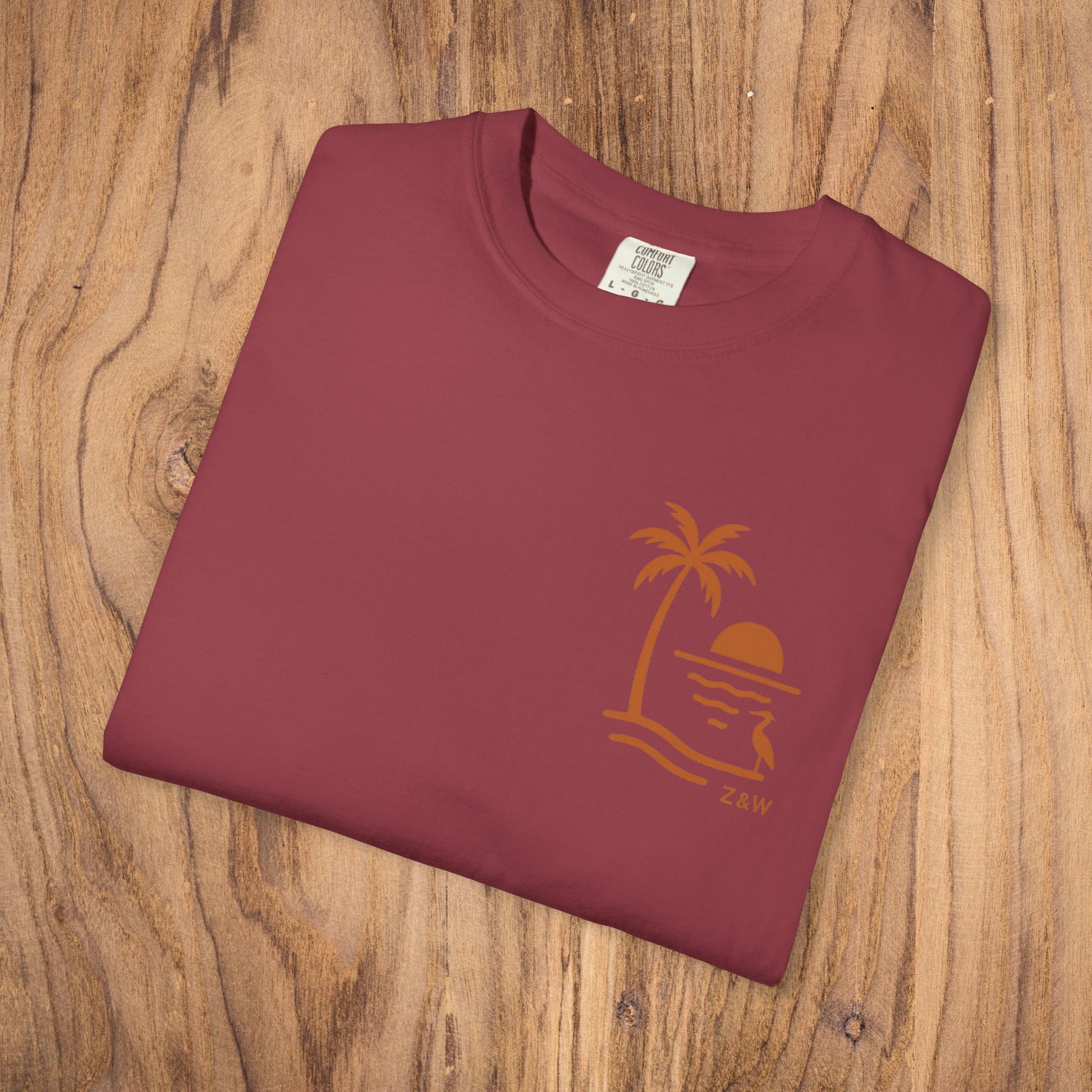 Unisex Sunset Palm Tree T-Shirt presented flat in a rich maroon color, featuring a unique palm tree and sunset graphic, crafted from vibrant garment-dyed cotton, ideal for both men and women.