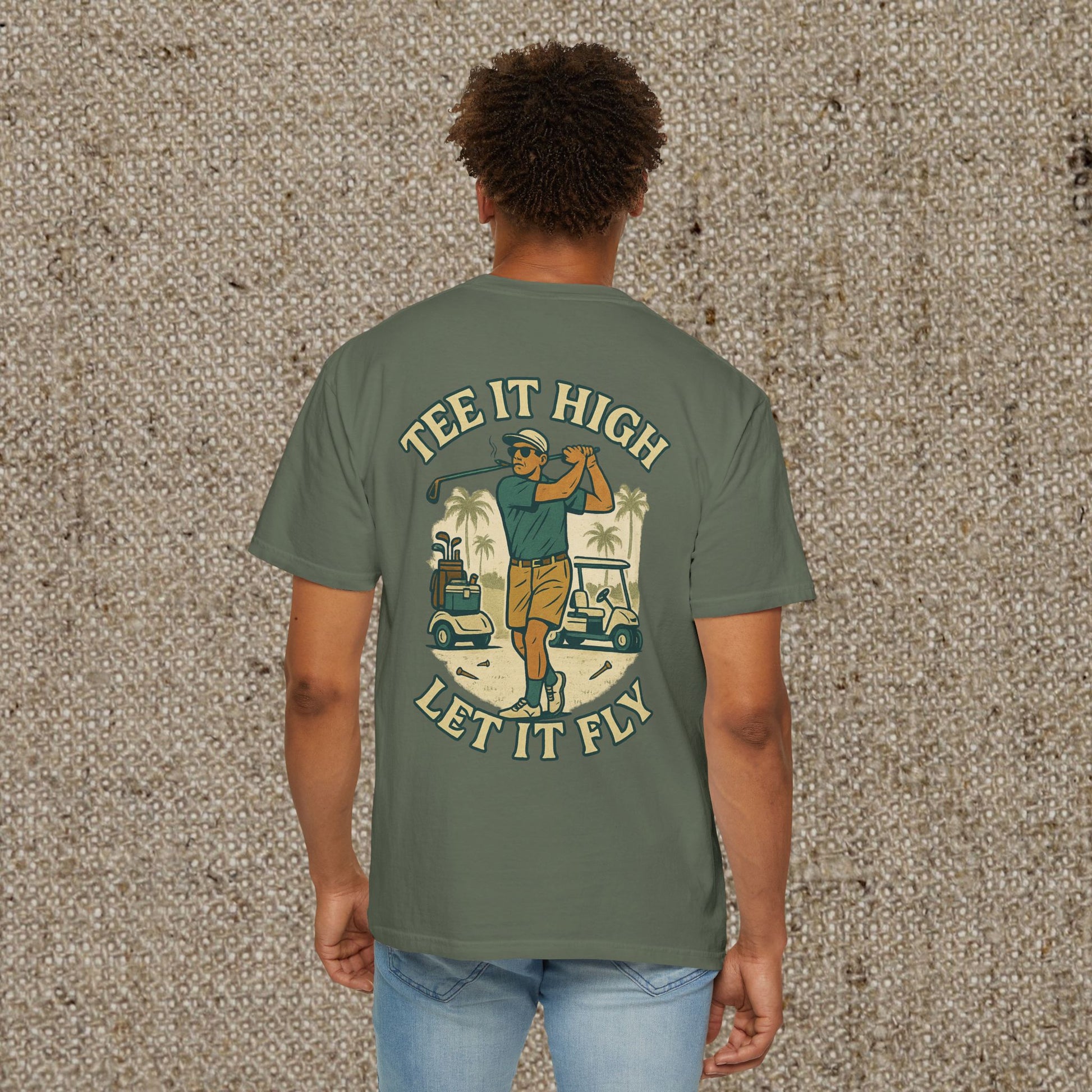 Tee It High Let It Fly Graphic Tee featuring a golfer in action, printed on a soft olive green US cotton fabric. Perfect for golf enthusiasts looking for a stylish and durable tee.