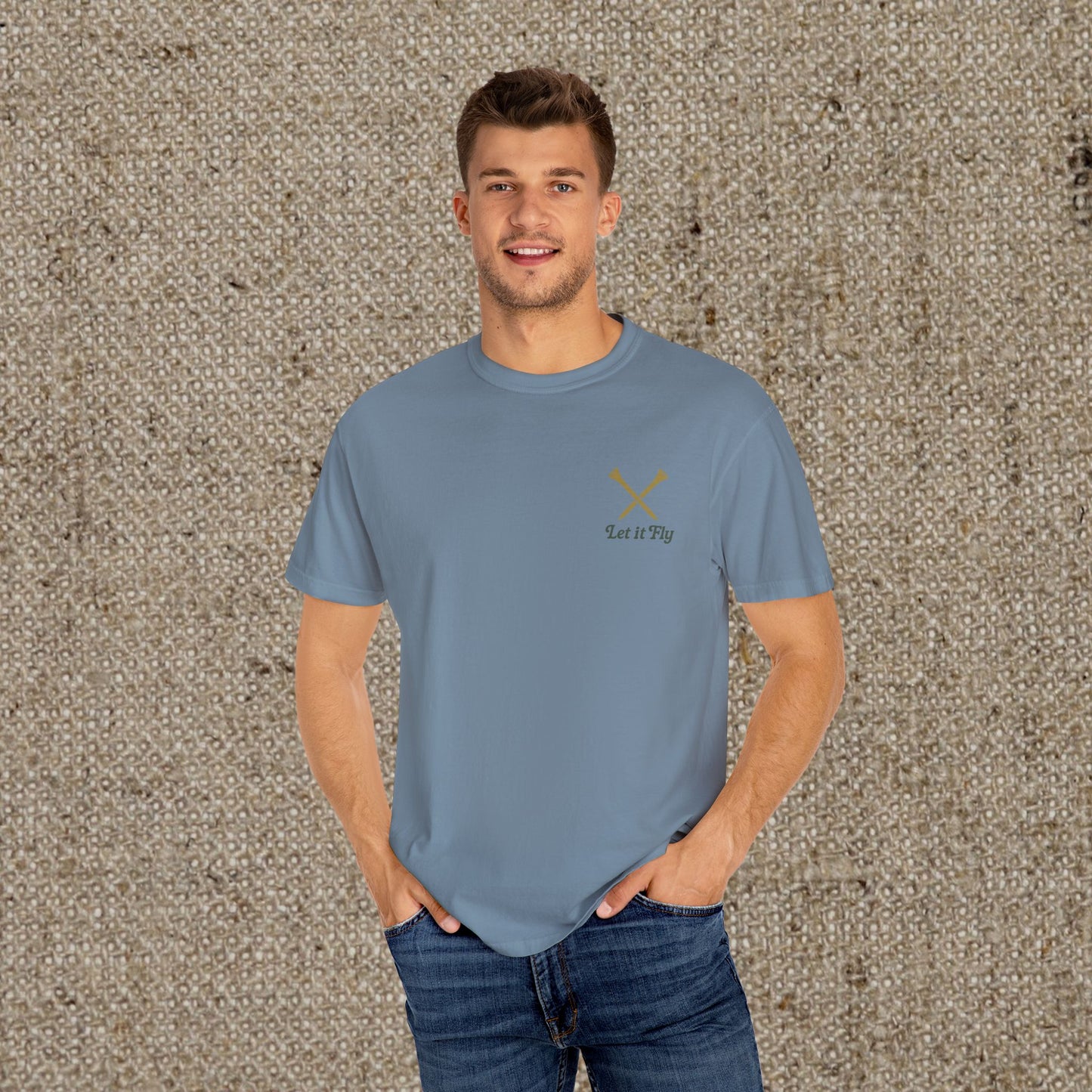 Model wearing the stylish Tee It High Let It Fly Graphic Tee in blue, featuring crossed clubs and 'Let It Fly' text, perfect for golf lovers.