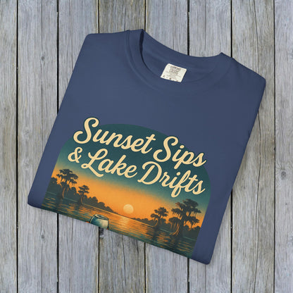 Folded Lake Drifts T-Shirt in deep navy color, showcasing the 'Sunset Sips & Lake Drifts' artwork on a wooden surface.