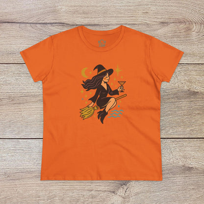 Witchy Night Out Tee in vibrant orange displaying a playful witch flying with an hourglass, surrounded by stars, made from ethically sourced 100% cotton for durability.