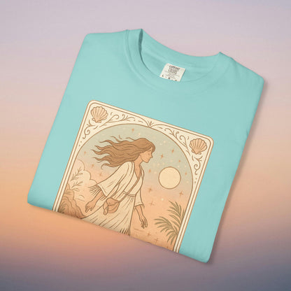 Wanderer Tarot Graphic Tee in vibrant turquoise, displaying a whimsical design of a woman in a serene landscape, perfect for expressing your individuality. Made responsibly from 100% cotton, available in sizes S to 4XL.