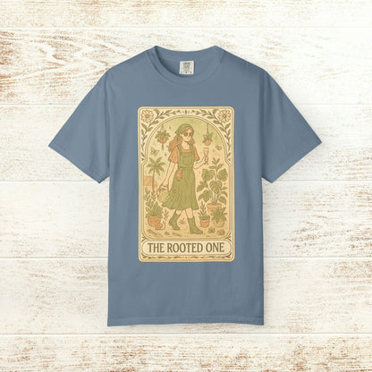 Rooted One Tarot Tee in light blue, featuring an enchanting design of a character alongside greenery. Ethically sourced cotton ensures comfort and sustainability.
