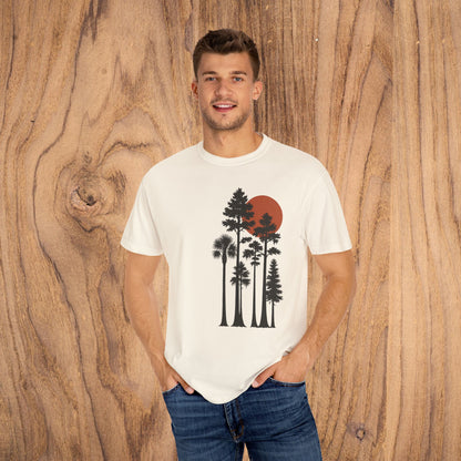 Model wearing Sunset Trees Unisex T-Shirt, highlighting the soft 100% cotton, garment-dyed fabric, and stylish design against a wooden backdrop.