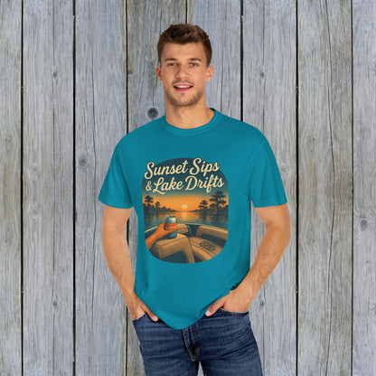 Model wearing the Lake Drifts T-Shirt in vibrant turquoise, featuring the design 'Sunset Sips & Lake Drifts' against a wood backdrop.