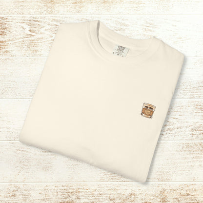 Rodeo On The Rocks Tee - Folded beige t-shirt featuring a drink design, representing soft 100% US cotton and unique garment-dyed style.