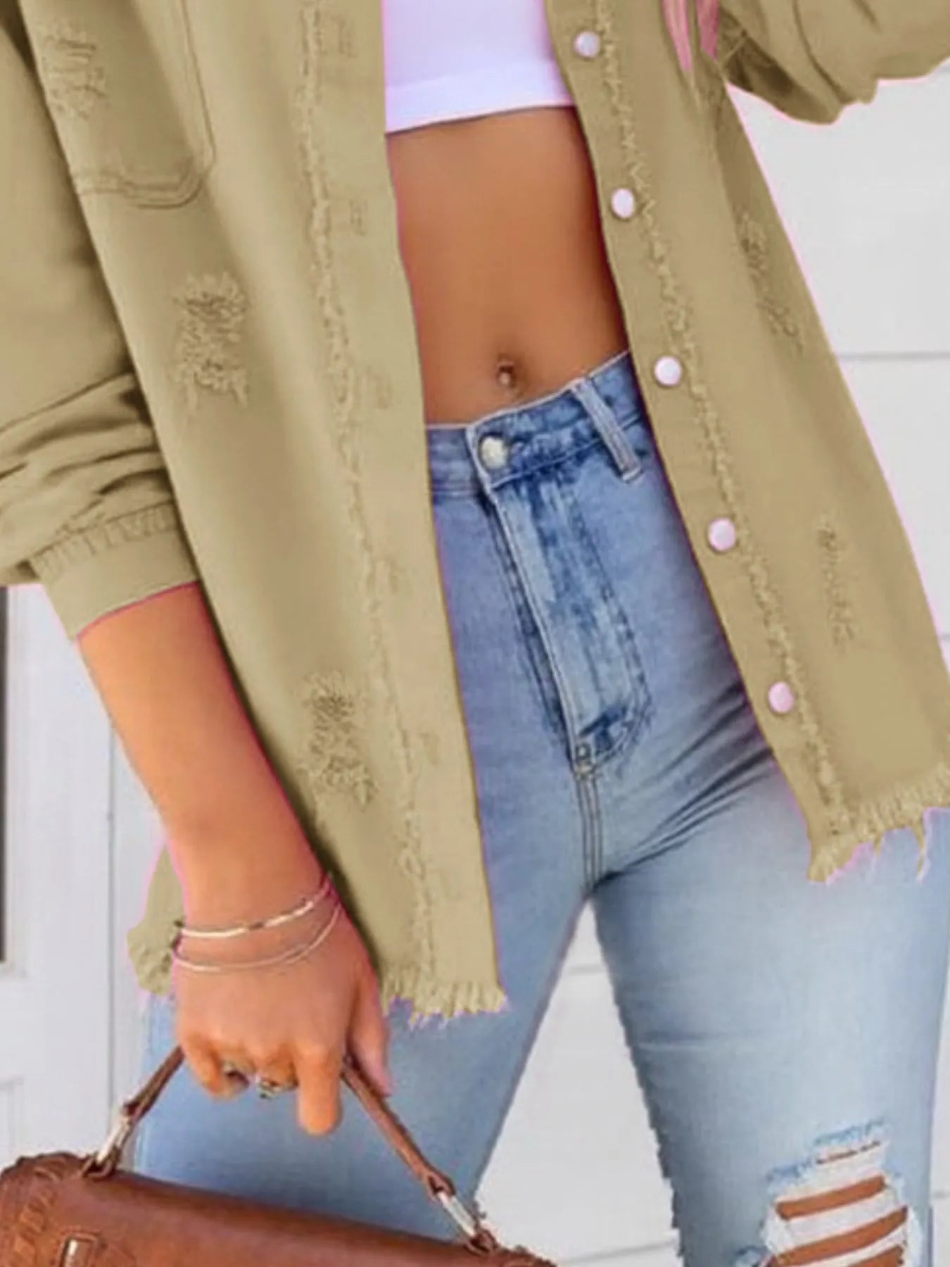 Close-up of the oversized distressed denim jacket with frayed edges and buttoned pockets, perfect for casual wear, complemented by high-waisted jeans.