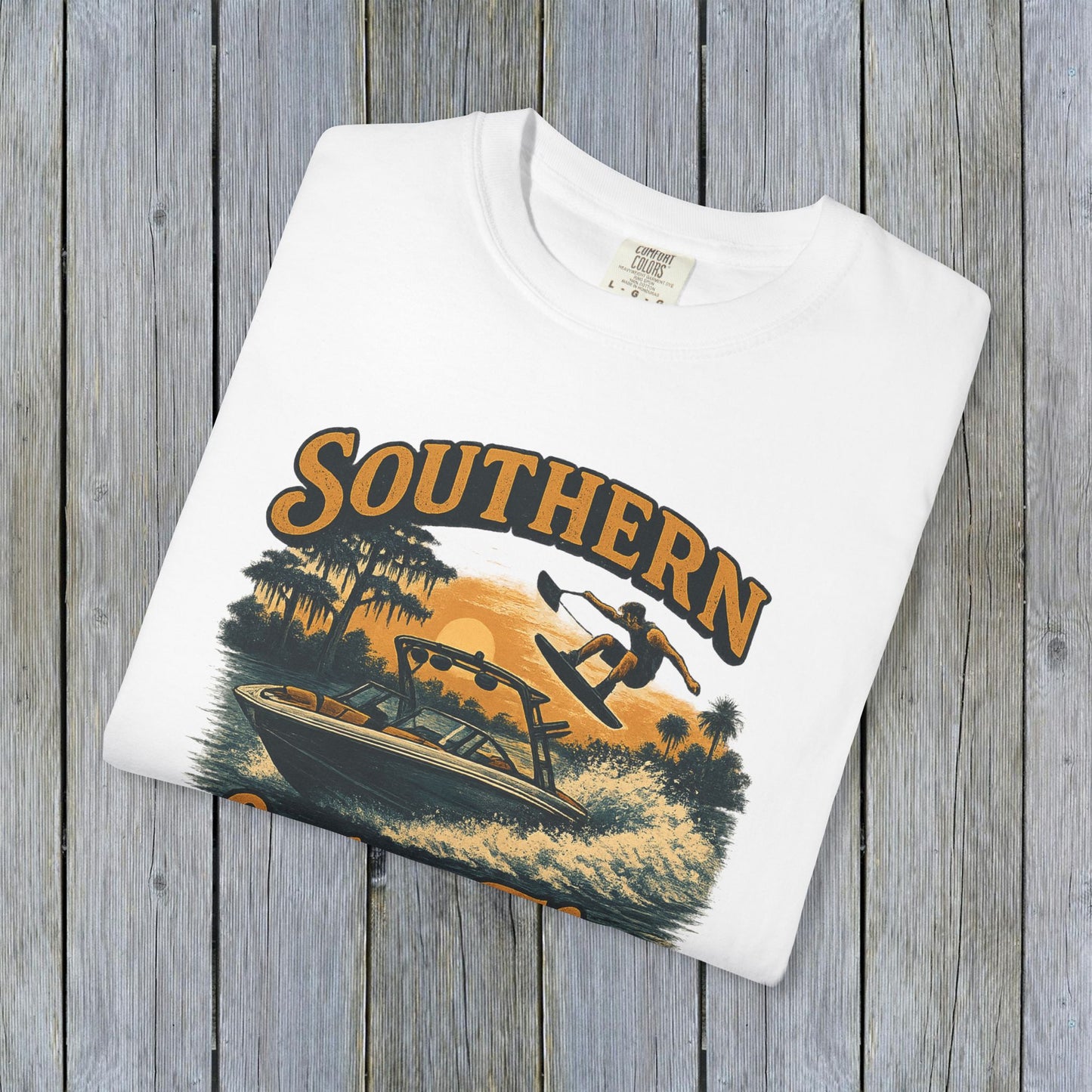 Southern Lake Flow T-Shirt featuring a stunning graphic design of a wakeboarder and boat on a lake, showcasing eco-friendly 100% US cotton material, ideal for outdoor enthusiasts.