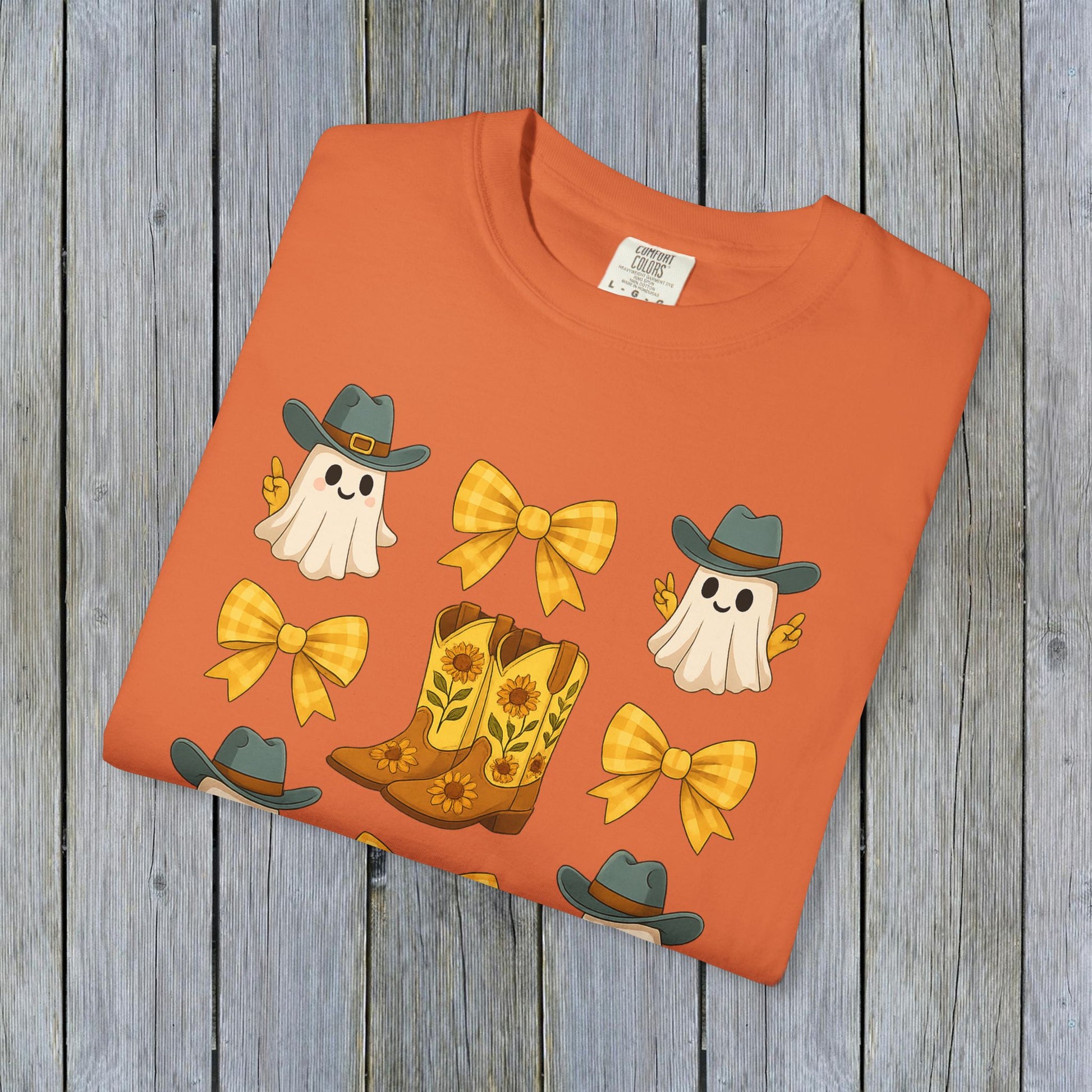 Cute Halloween T-Shirt in vibrant orange showcasing a fun design of ghosts and cowboy boots, perfect for unisex fall fashion and made from eco-friendly fabric.