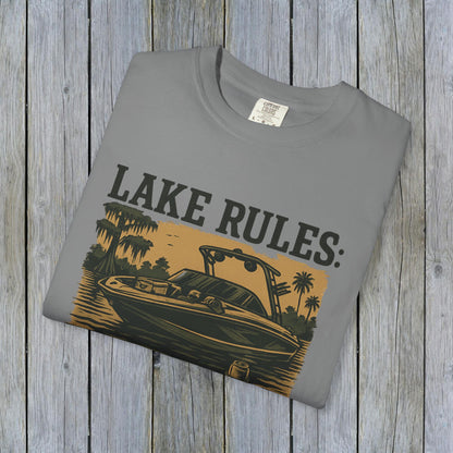 Folded Unisex Garment-Dyed Lake Rules Tee displayed on rustic wood, featuring bold lake rules branding ideal for casual outings.