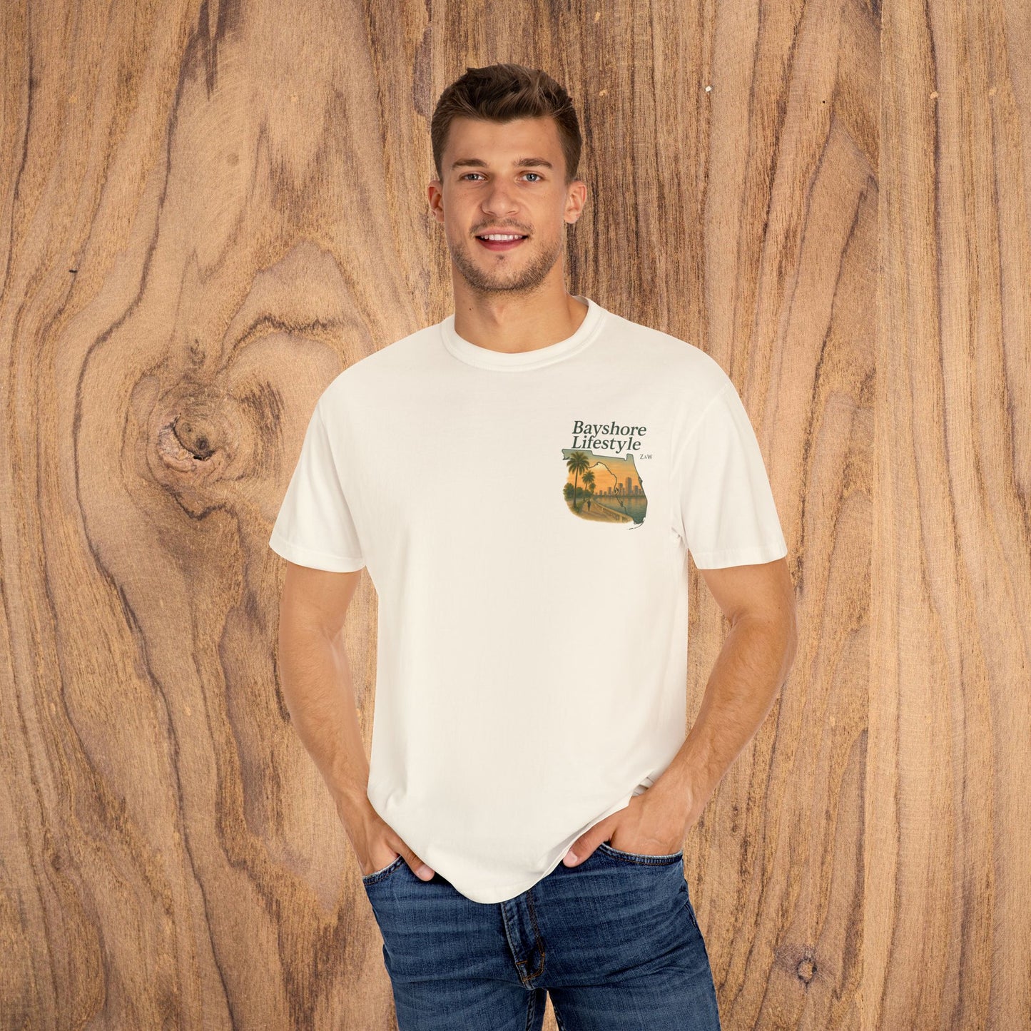 Bayshore Lifestyle Tee - Front view of a man wearing a lightweight, 100% cotton t-shirt with a scenic graphic, set against a wooden background.